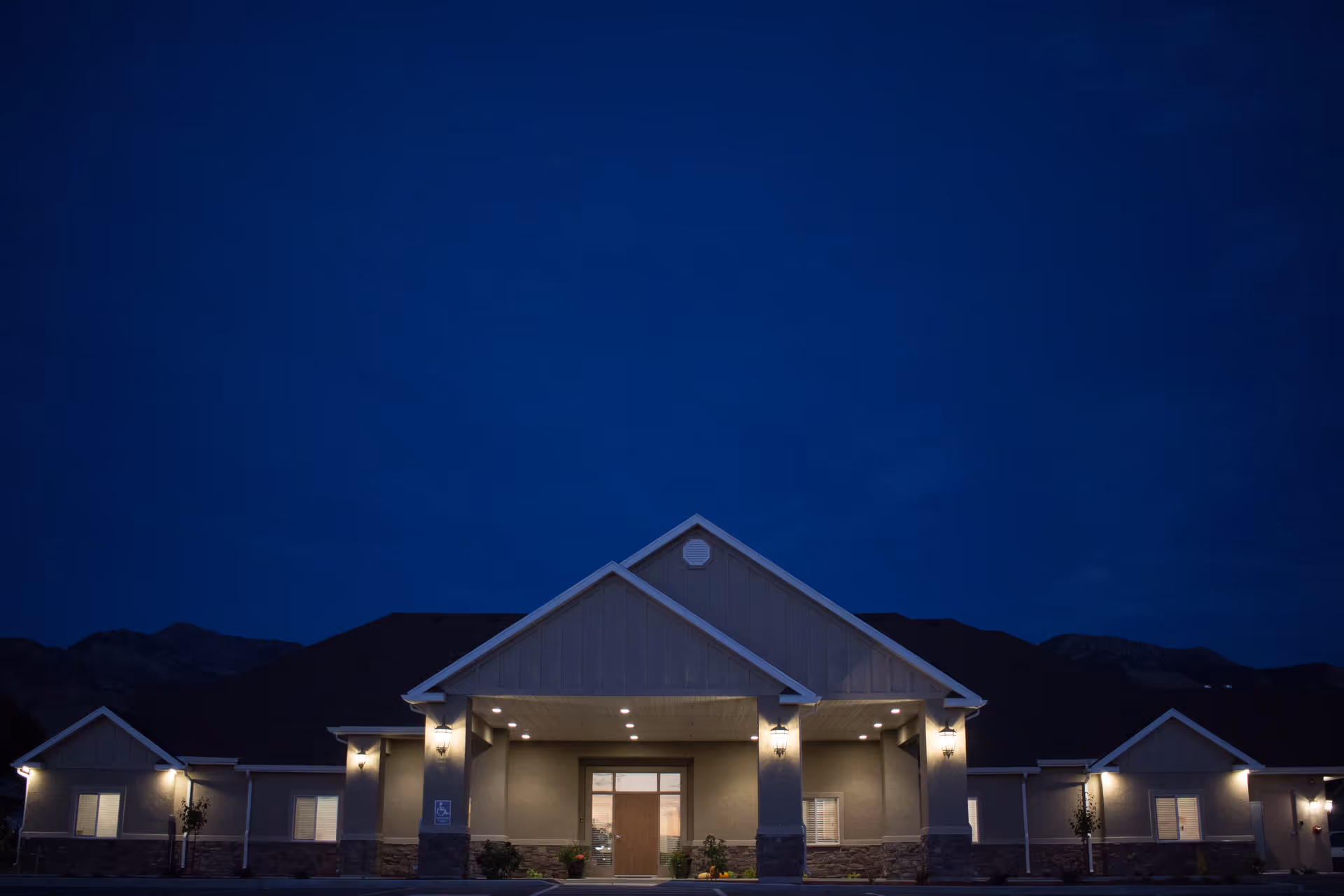 Nighttime exterior of Autumn Care Living Center with illuminated front entrance under a dark blue sky.