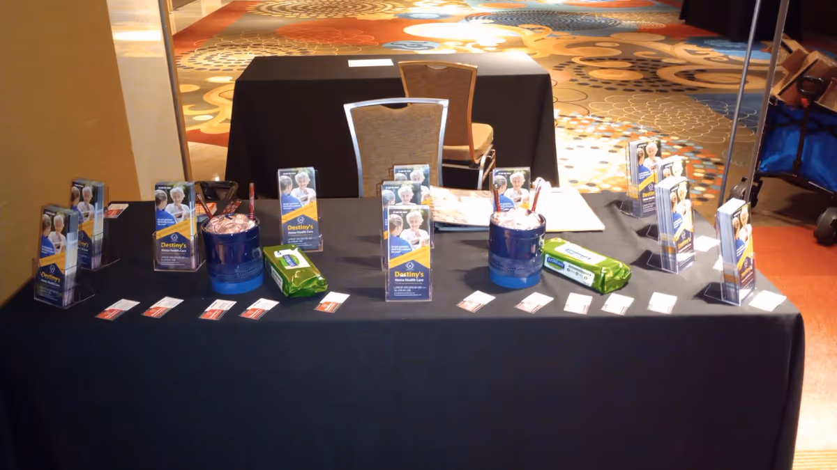 Promotional display table with Destiny's Home Health Care brochures at an indoor event.