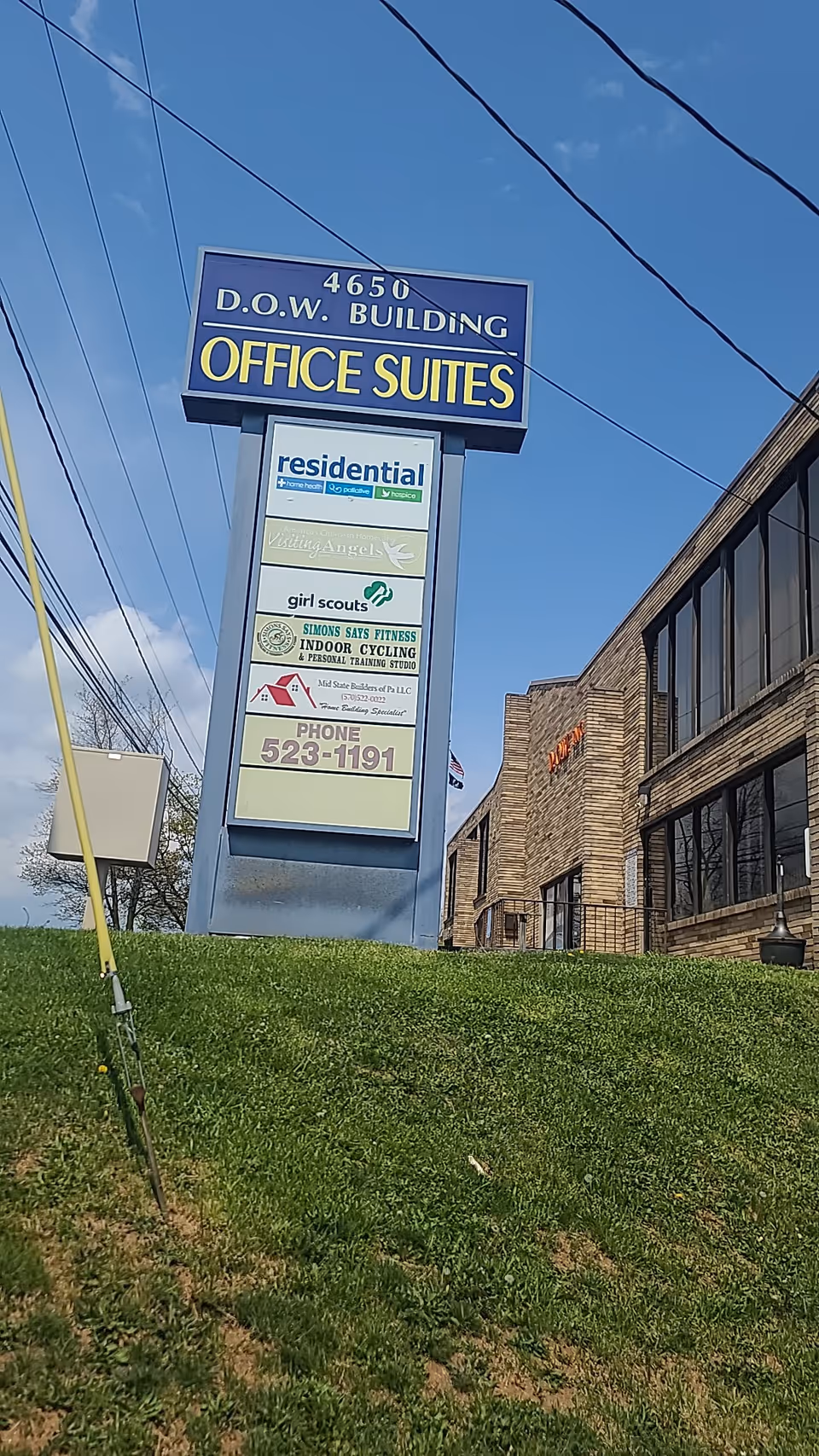 Tall blue sign advertising office suites and residential services beside a brick building exterior.