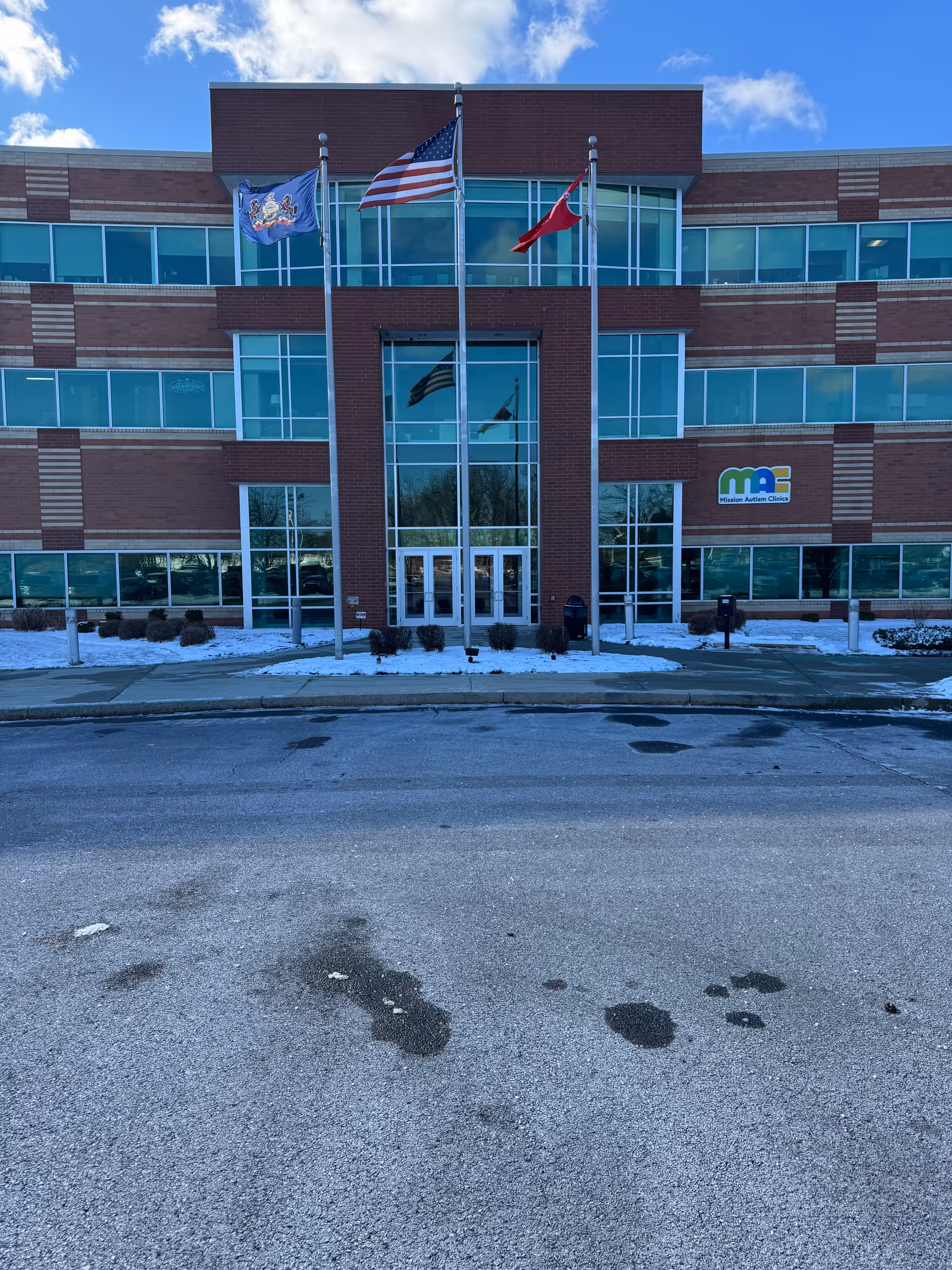Brick Maxim Healthcare Harrisburg office with glass entrance and three flags in front.