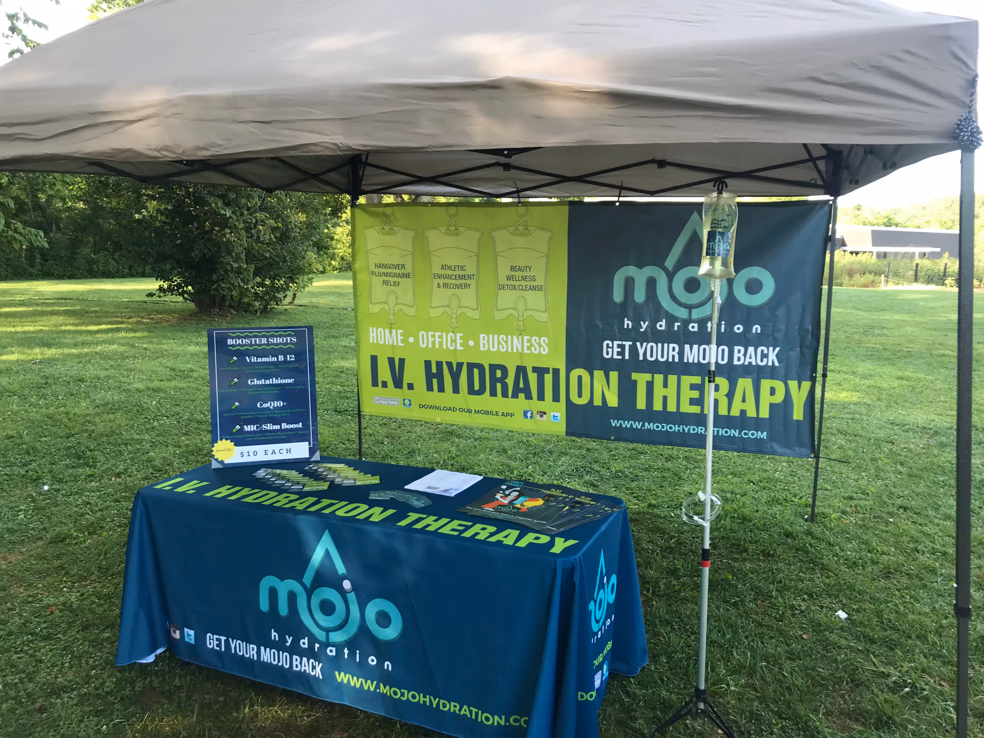 Outdoor Mojo Health & Hydration booth with IV hydration banners under a canopy