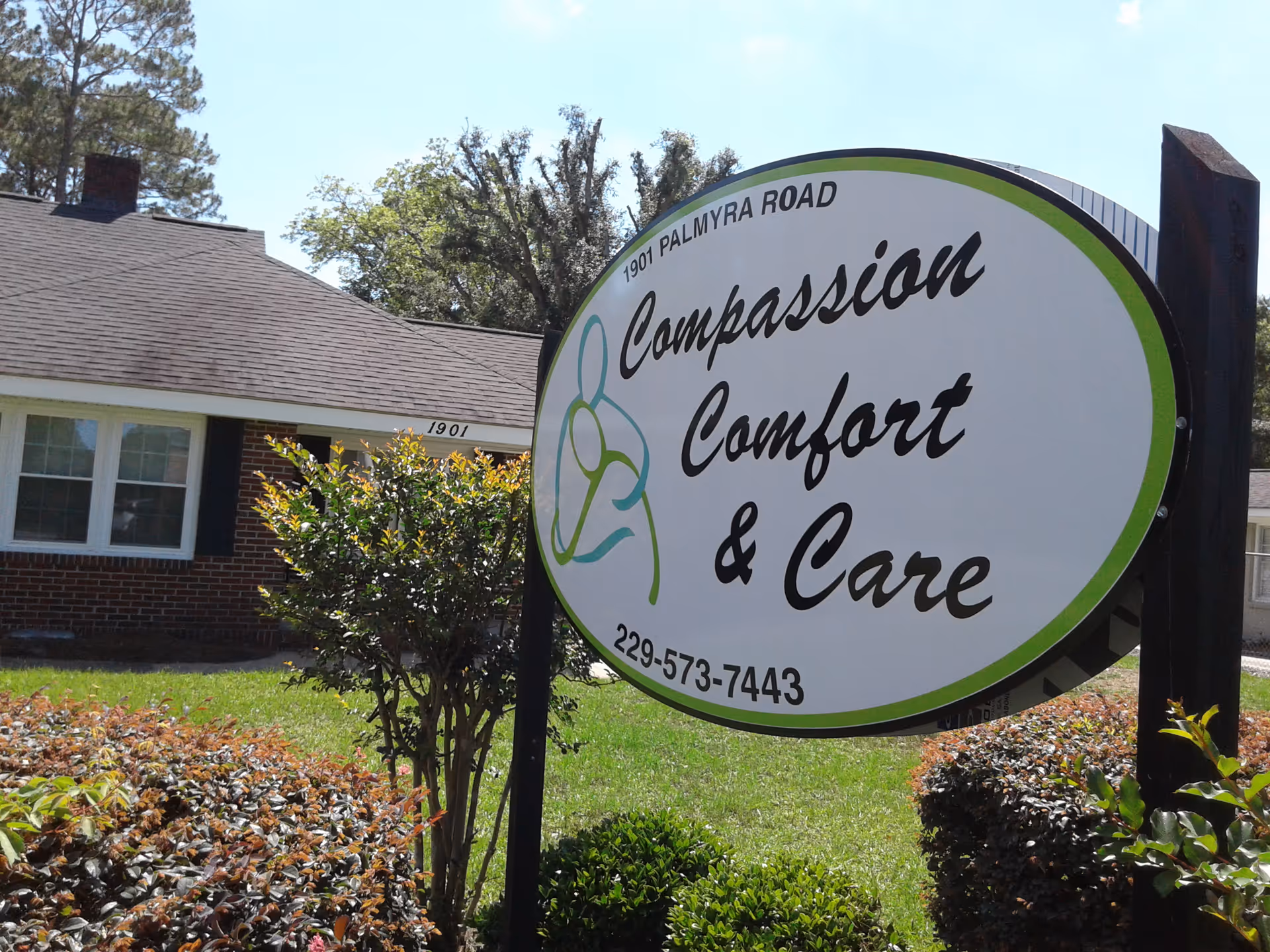 Large outdoor sign reading Compassion Comfort & Care beside a brick facility building