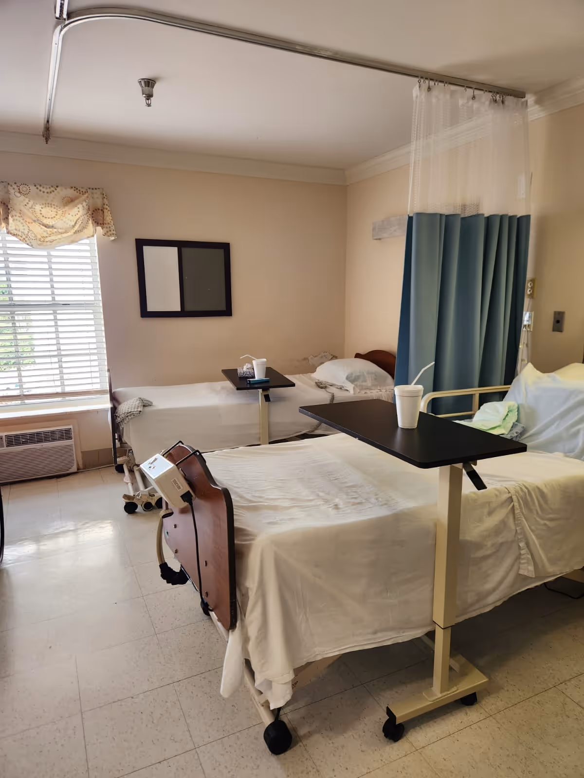 Two hospital-style beds with privacy curtain in a patient room.
