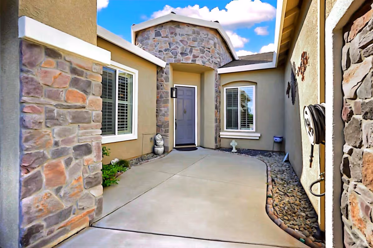 Courtyard entryway of a stone-faced senior care facility with a front door and windows.