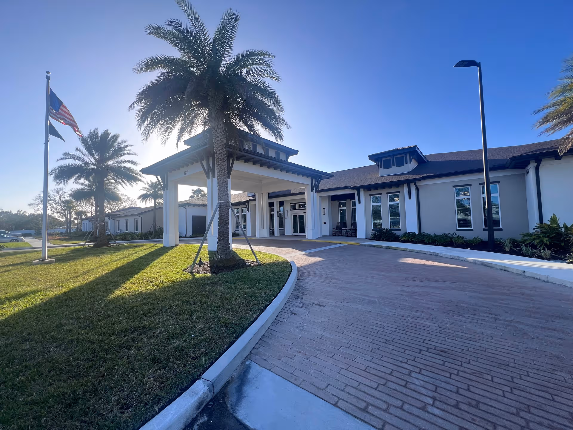 Exterior view of Alura Senior Living entrance with palm trees and canopy.