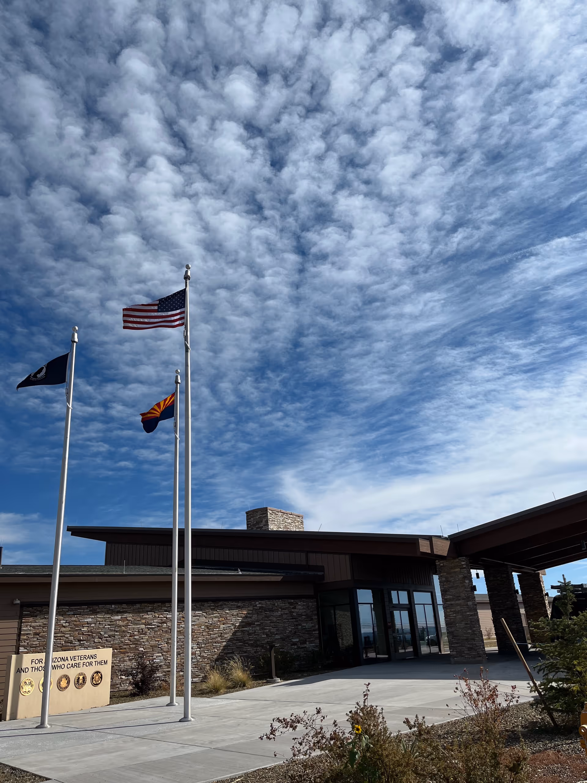 Front exterior of a modern veteran home with flagpoles by the entrance.