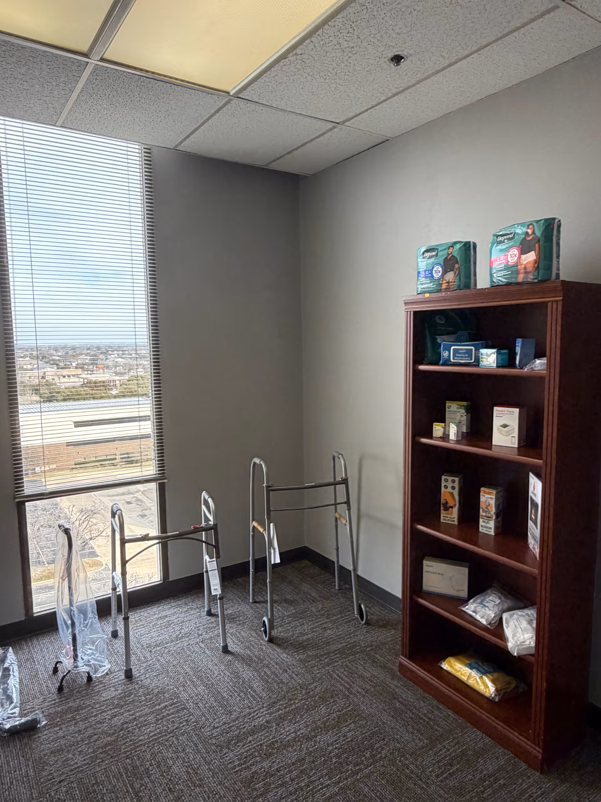 Corner interior with walkers, a shelf of medical supplies, and a window.