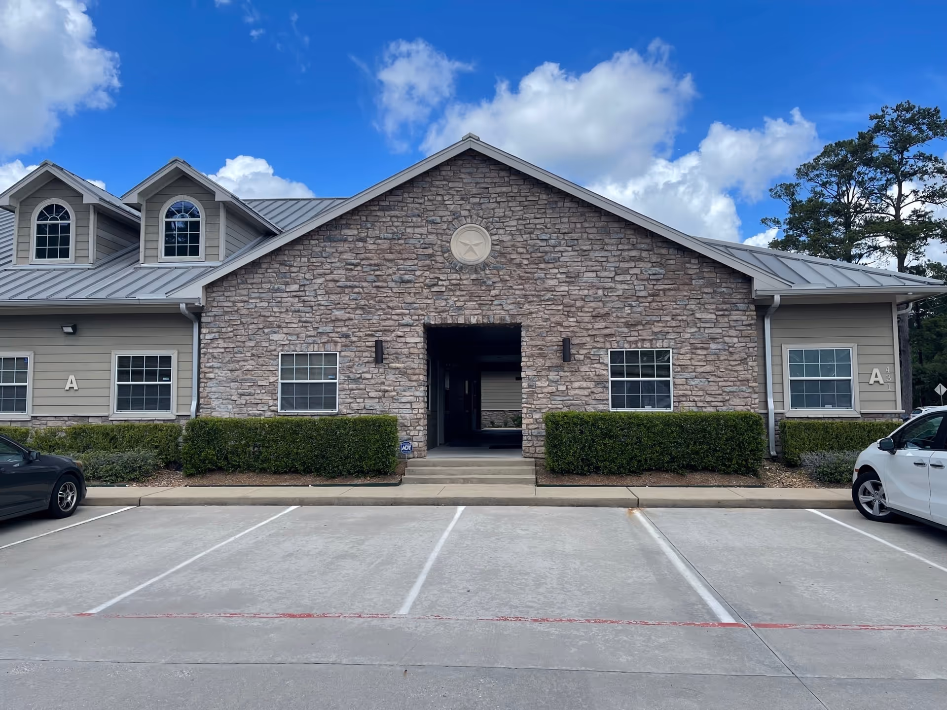Front view of a stone-clad senior living facility with parking spaces.