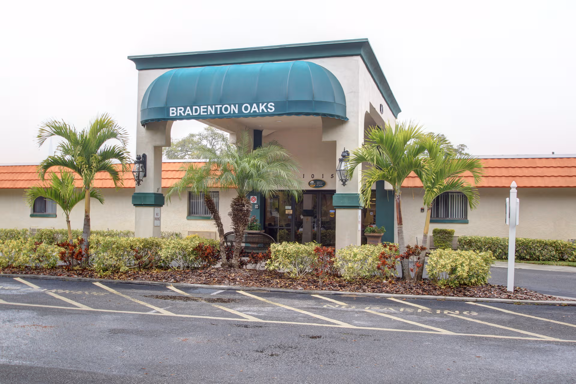 Exterior view of Bradenton Oaks entrance with teal awning and landscaping.
