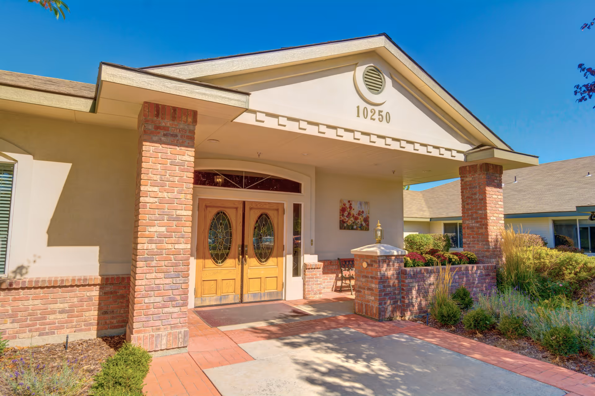 Senior living facility exterior with brick columns and wooden double doors at the entrance.