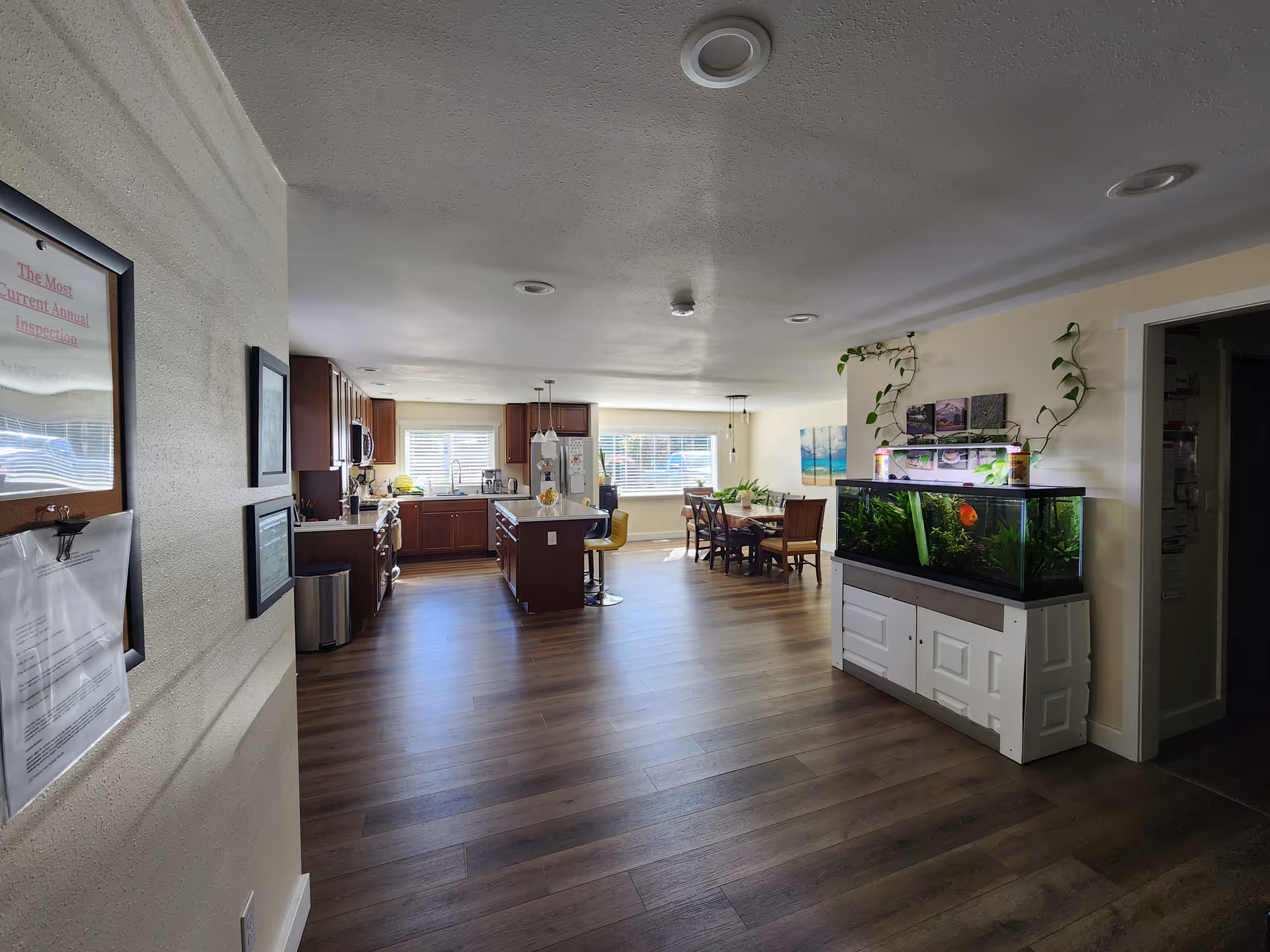 Open, well-lit communal area with kitchen island, dining table, and a large aquarium.
