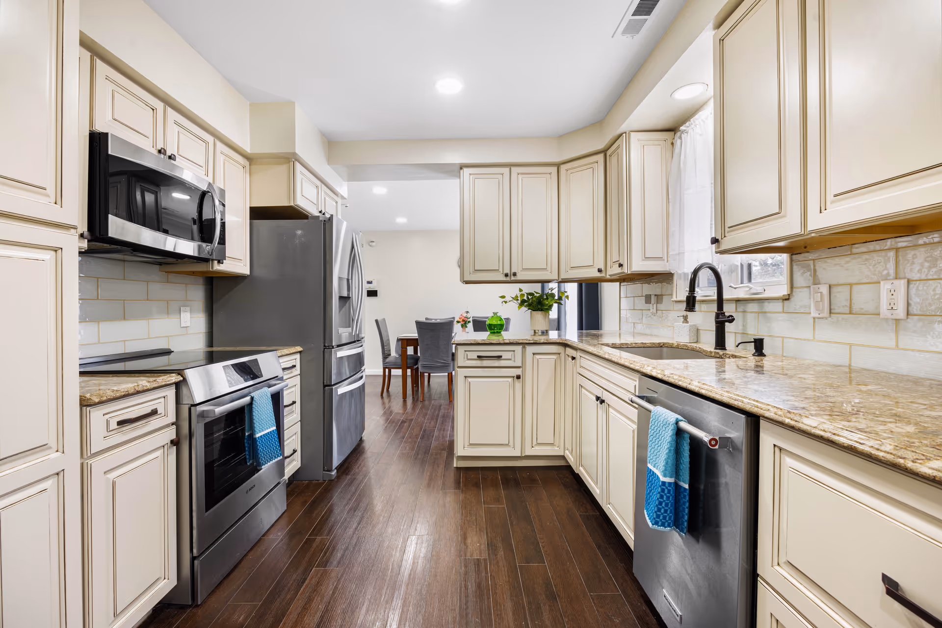 Cream kitchen cabinets flank stainless appliances and granite countertops in a bright modern kitchen.