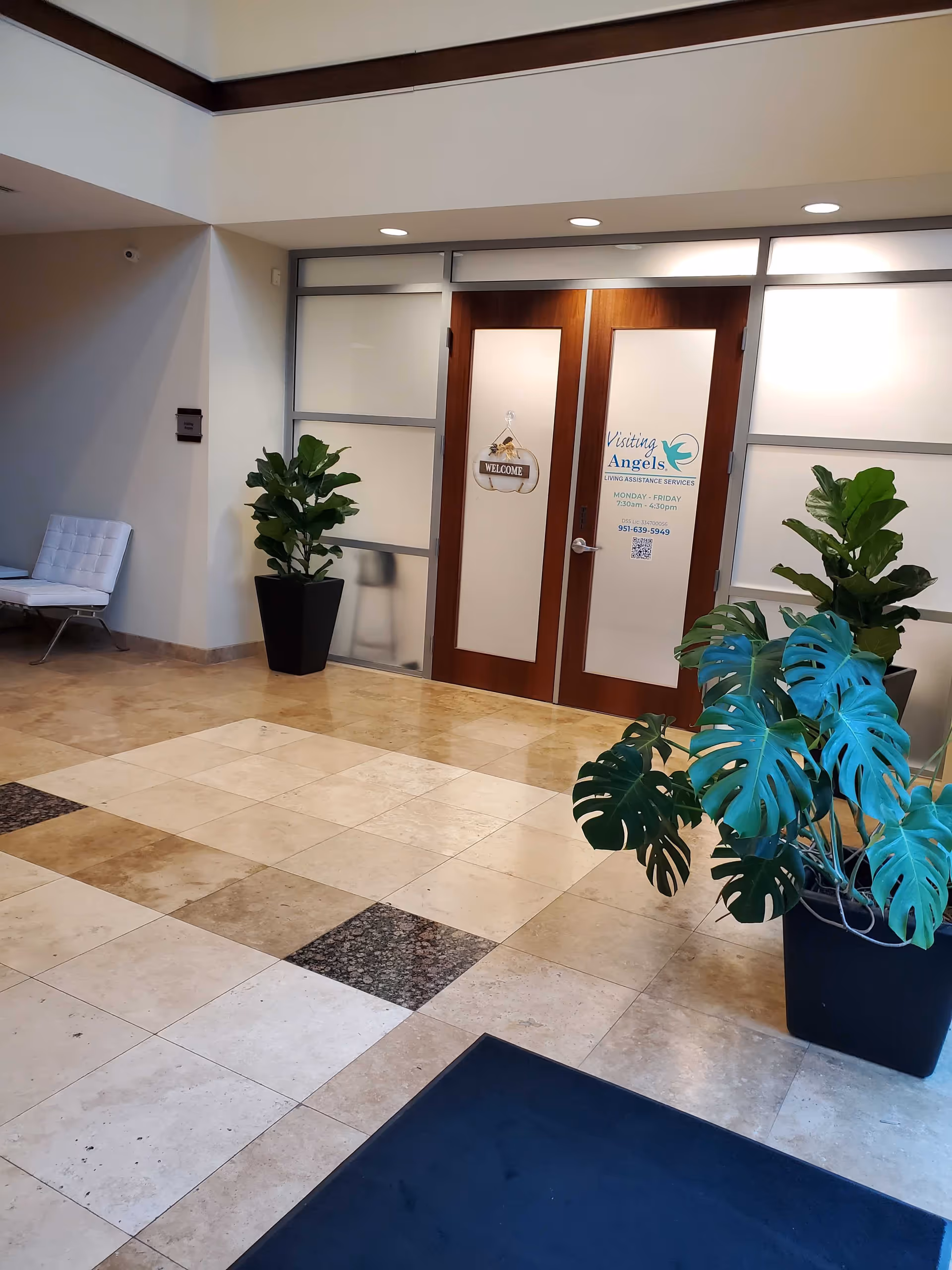 Lobby entrance with double wooden doors, glass panels, and potted plants.