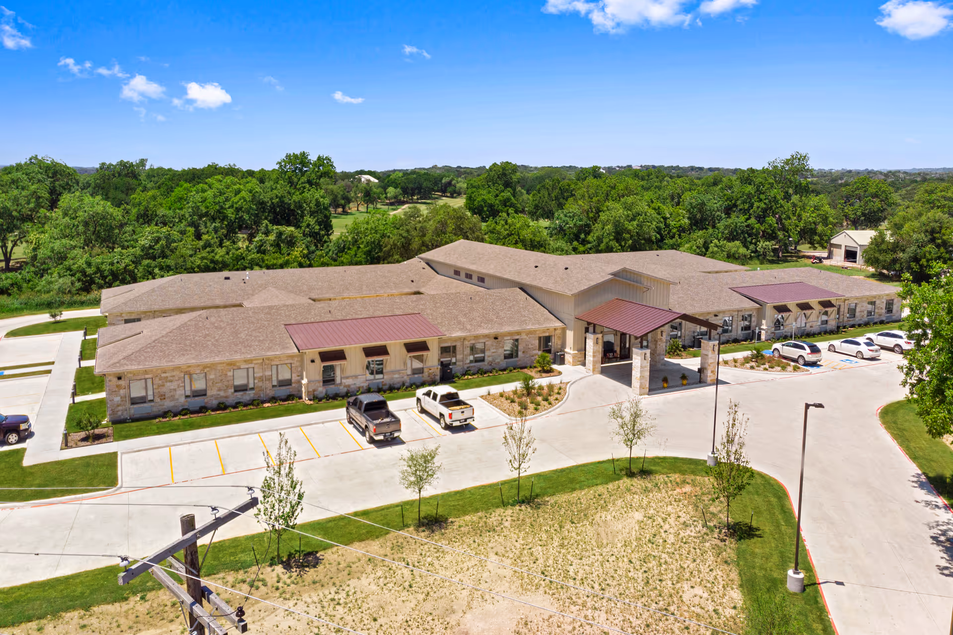 Aerial view of Lampasas Assisted Living building with a long light-brown roof and parking lot.