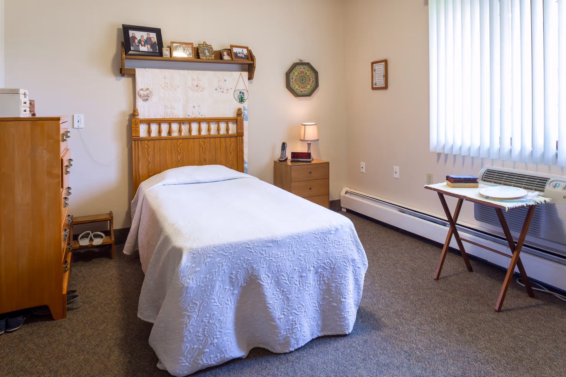 A neat bedroom in a Liberty senior living facility with a single bed and dresser.