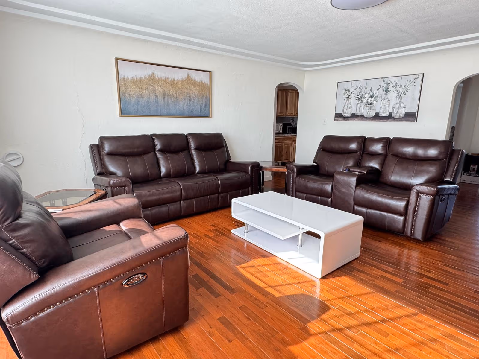 Cozy living room with brown leather sofas, a white coffee table, and wooden flooring.