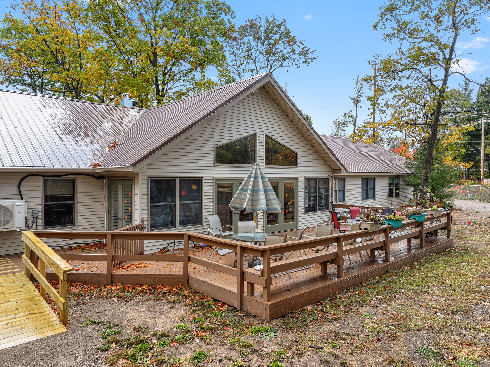 Single-story care facility with a large wooden deck, outdoor seating, and potted plants.