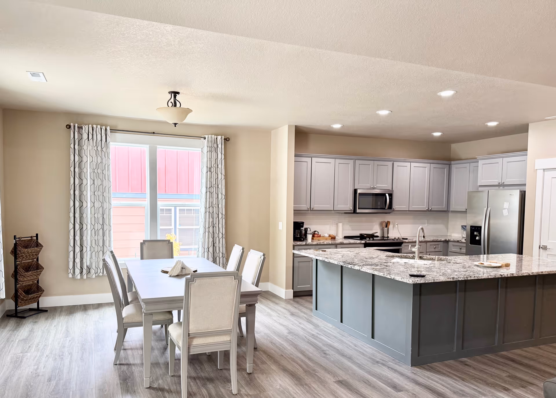 Open-concept kitchen and dining area in a senior living facility with a gray island.