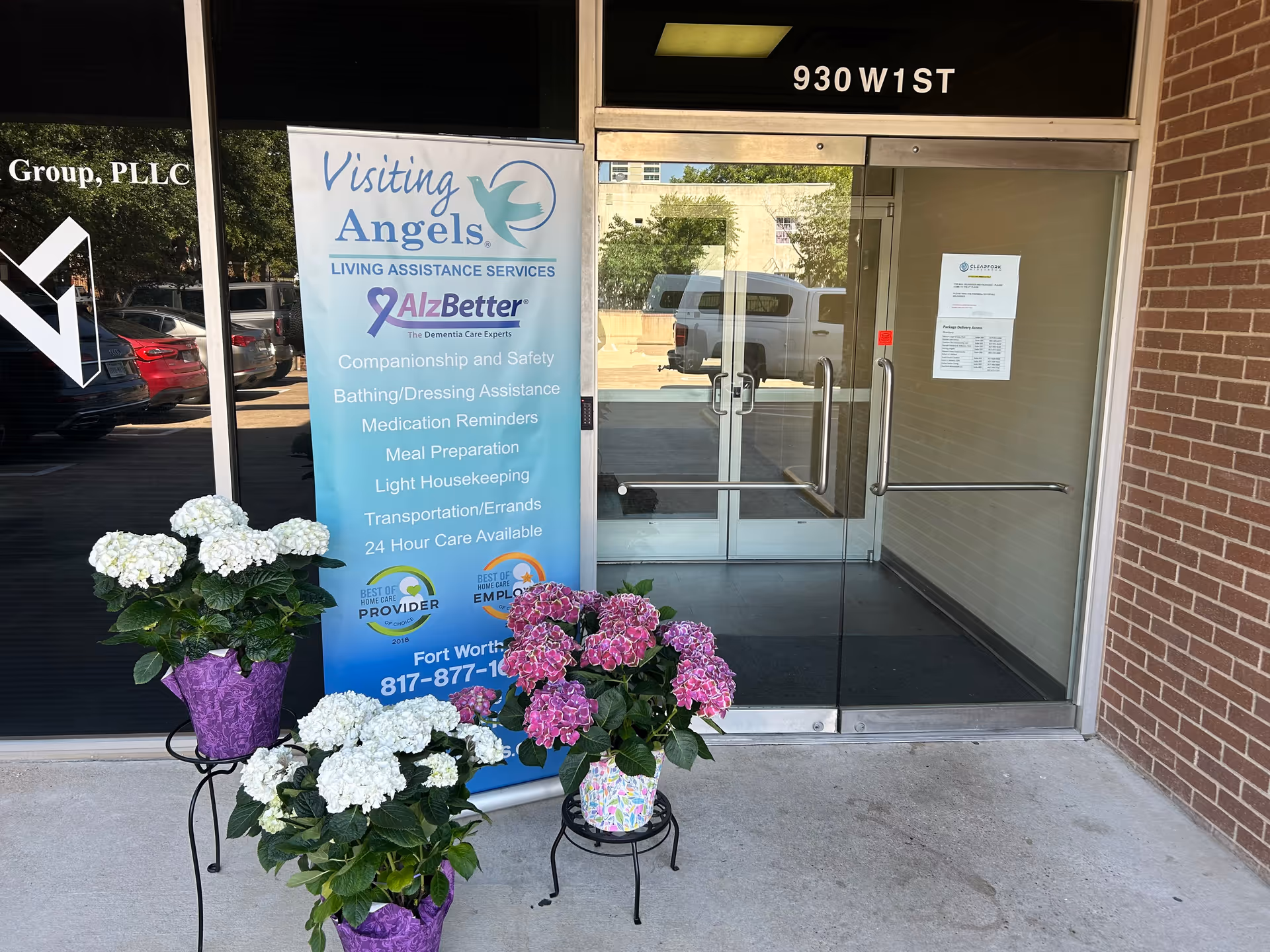 Exterior entrance of Visiting Angels facility with banner and potted flowers outside.