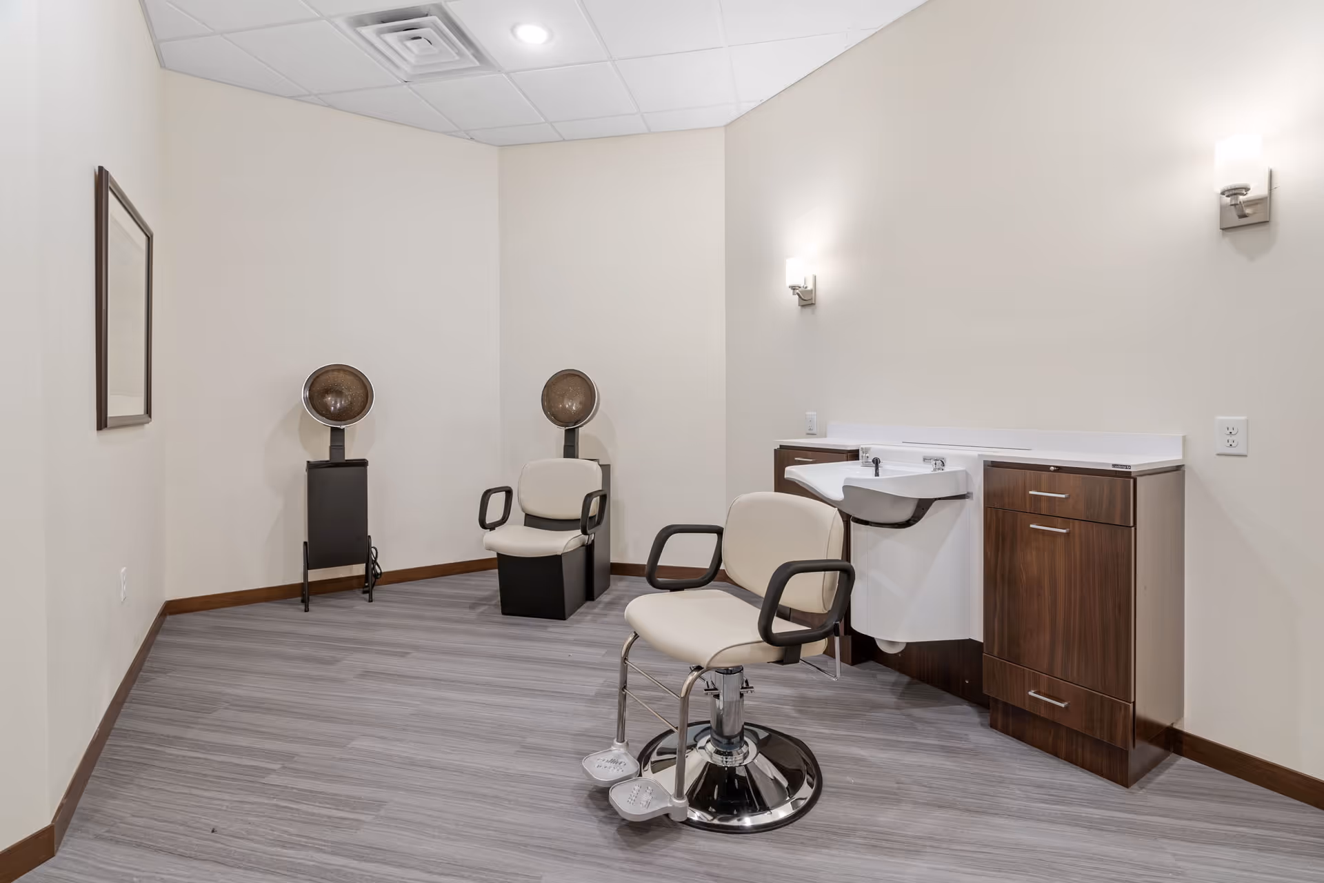 Salon area inside a senior living facility with chairs, hair dryers, and a sink.