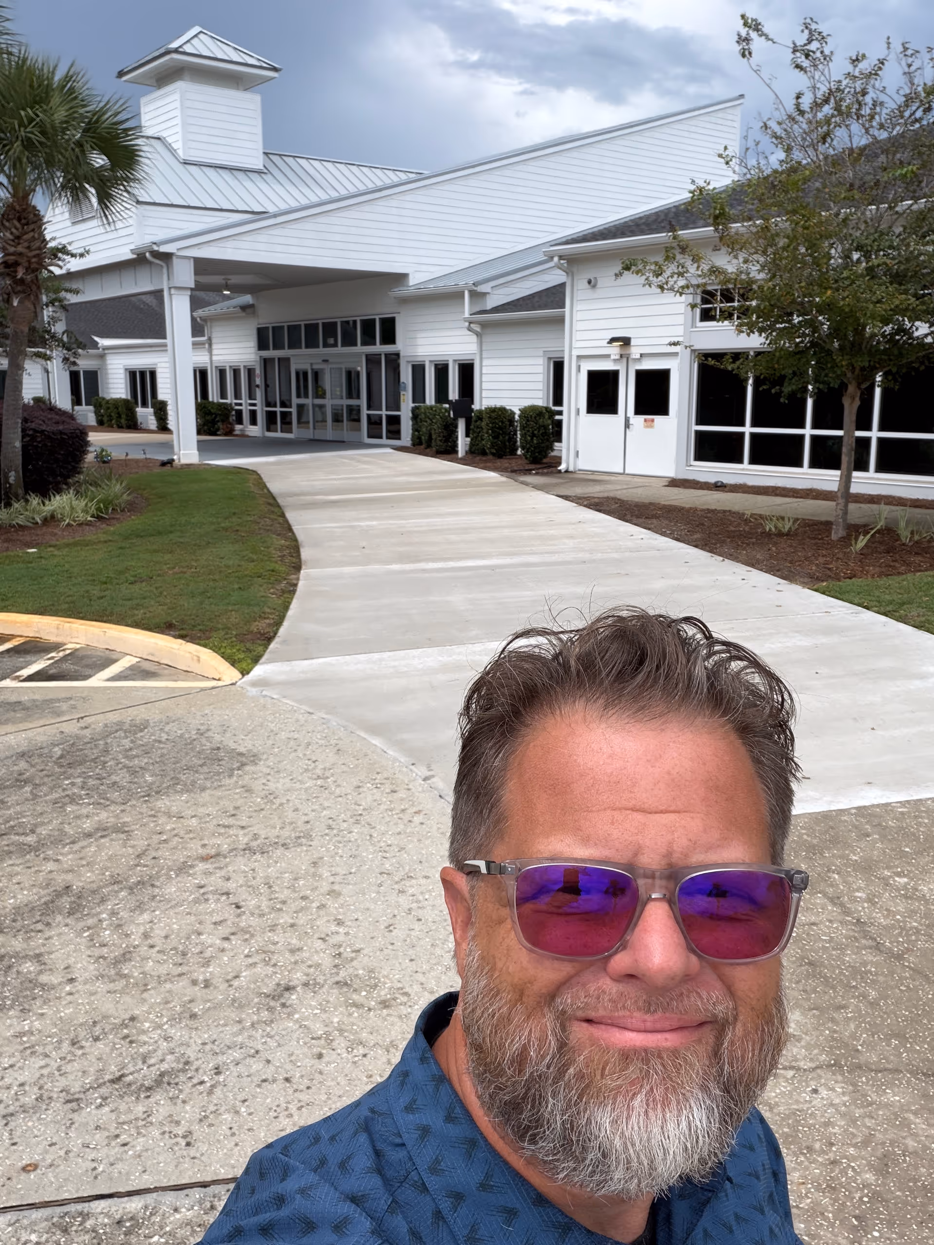 Man takes a selfie outside the Community Health & Rehabilitation Center entrance.