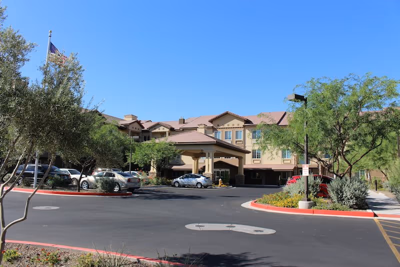 Senior living facility with a front entrance, covered drop-off area, and surrounding landscaping.