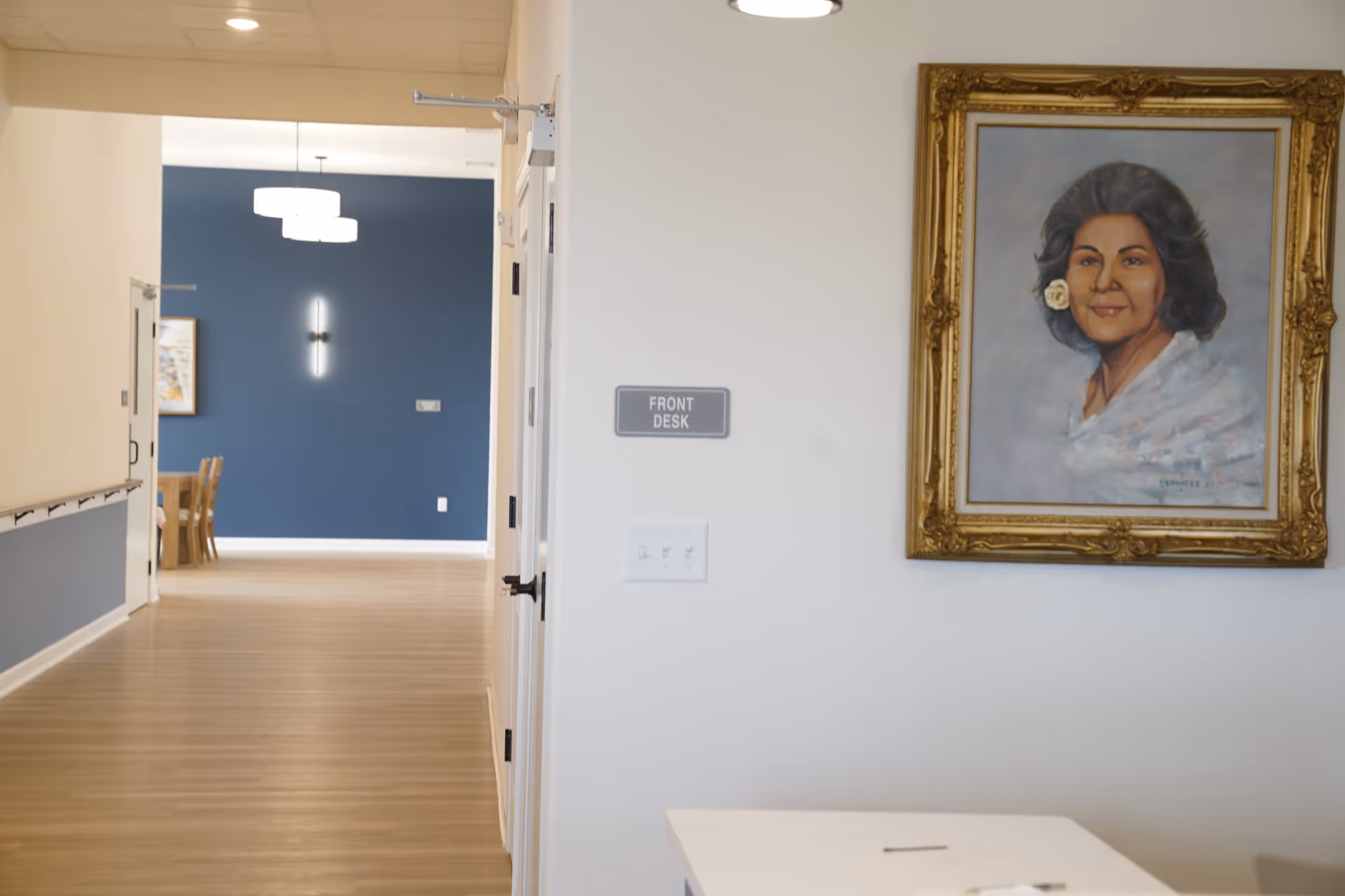 Bright hallway inside Anita's Gardens of Brookfield with a portrait and front desk sign.