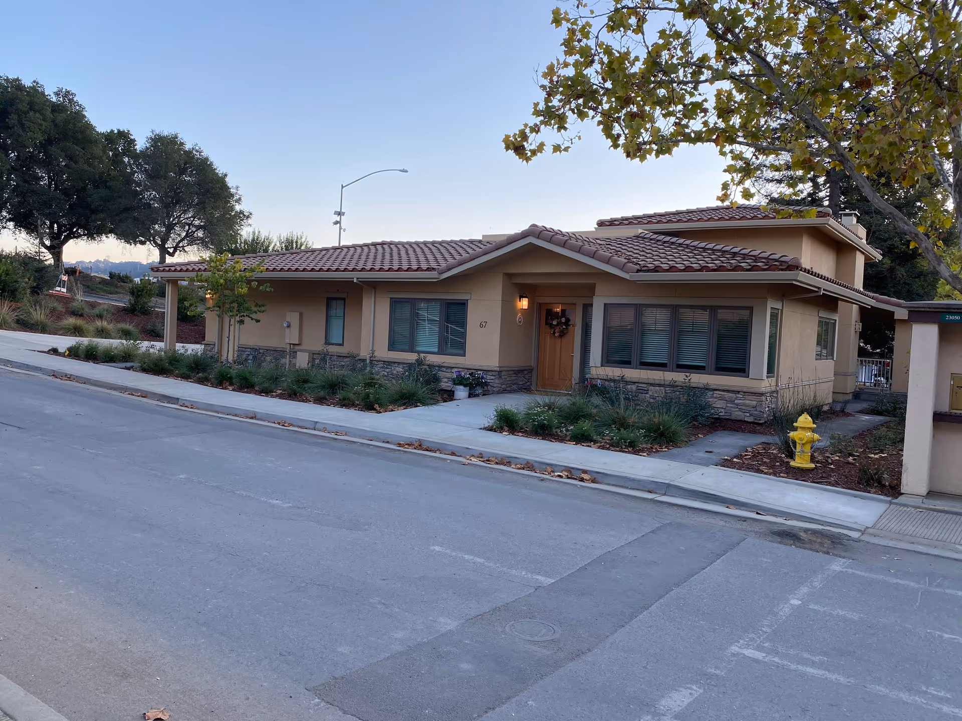 Front exterior view of a beige, single-story senior living building with neatly landscaped surroundings.