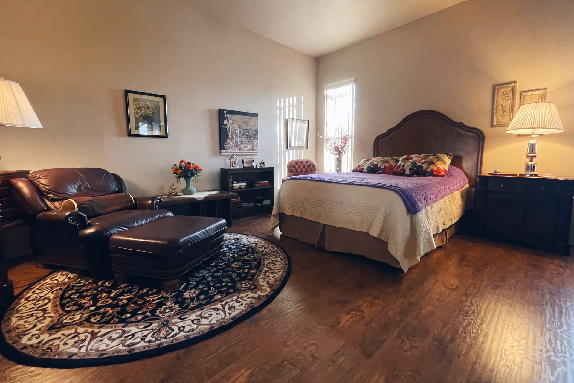 In Fountainview Assisted Living Home, a cozy bedroom features a bed, leather seating, and warm lighting.