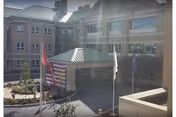 Exterior view of the Gino J Merli Veterans Center entrance with flags and a shaded canopy.
