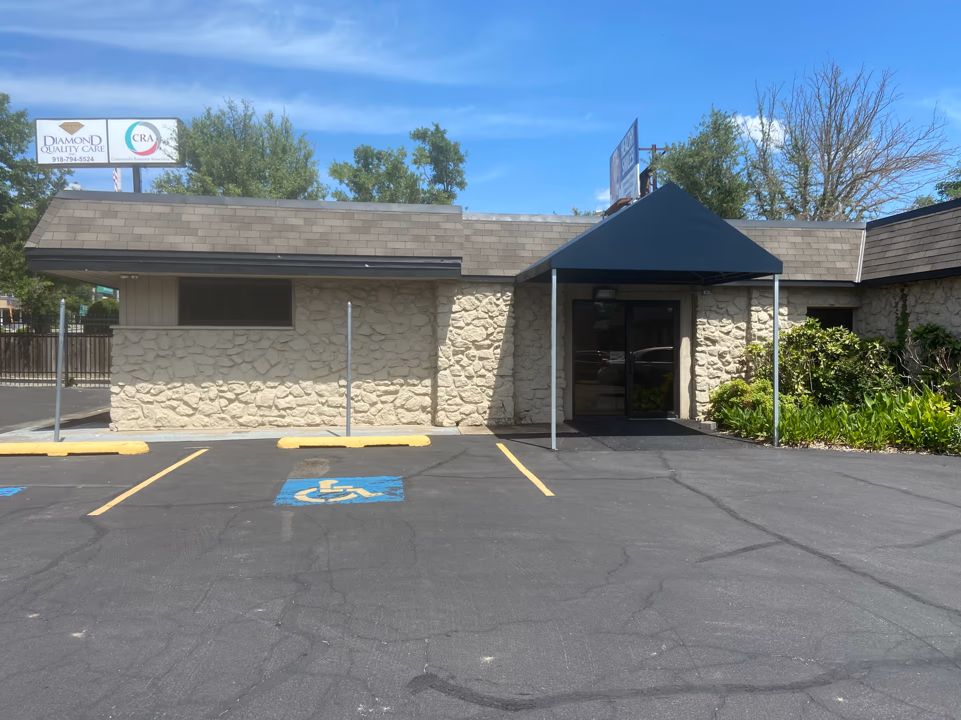 Exterior view of Diamond Quality Care facility with stone facade, blue canopy, and handicapped parking.