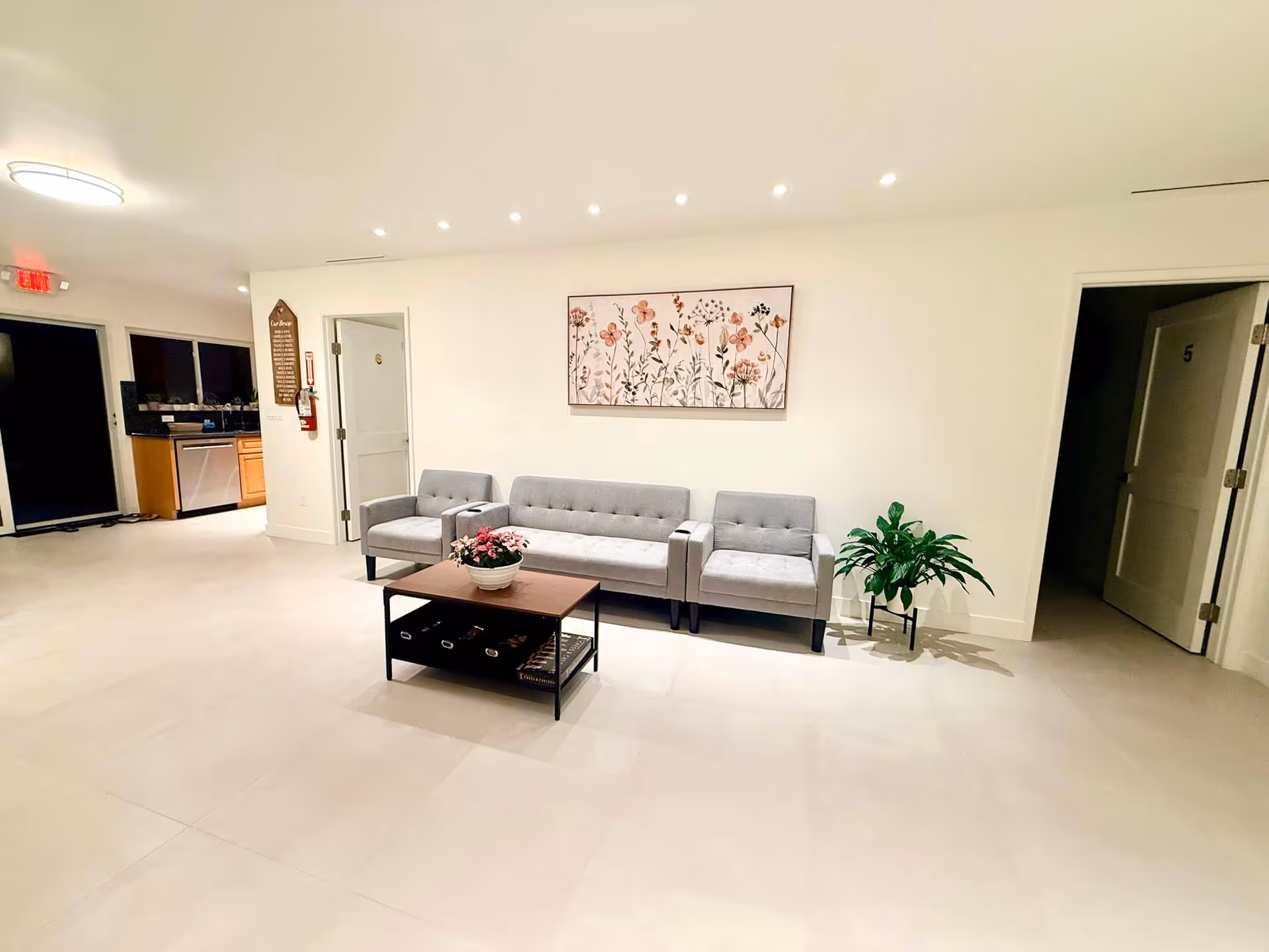 Bright lobby area with gray sofas, a central coffee table, plant, and wall art.