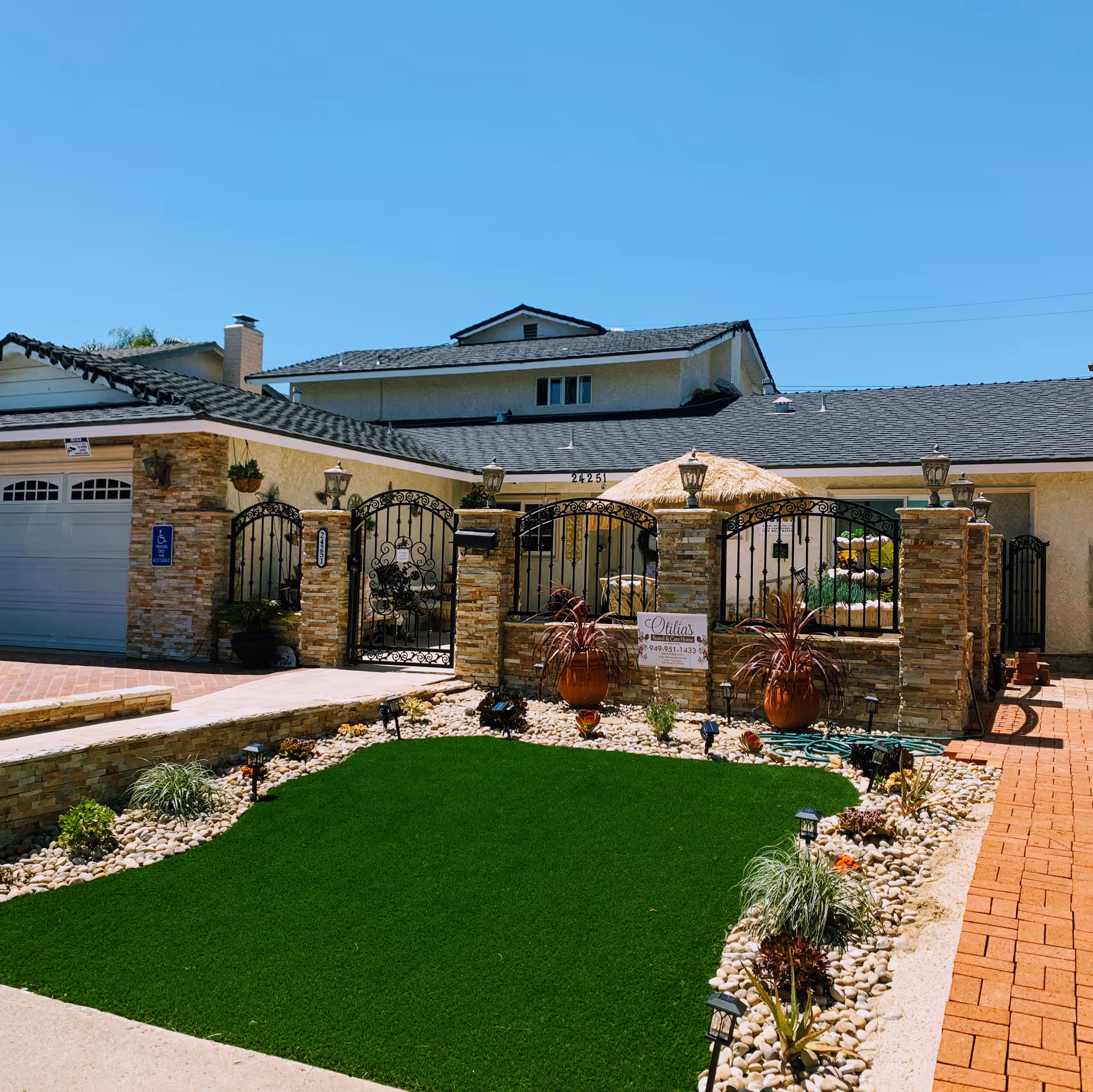 Exterior view of Otilia's Board and Care gated entrance with stone pillars.