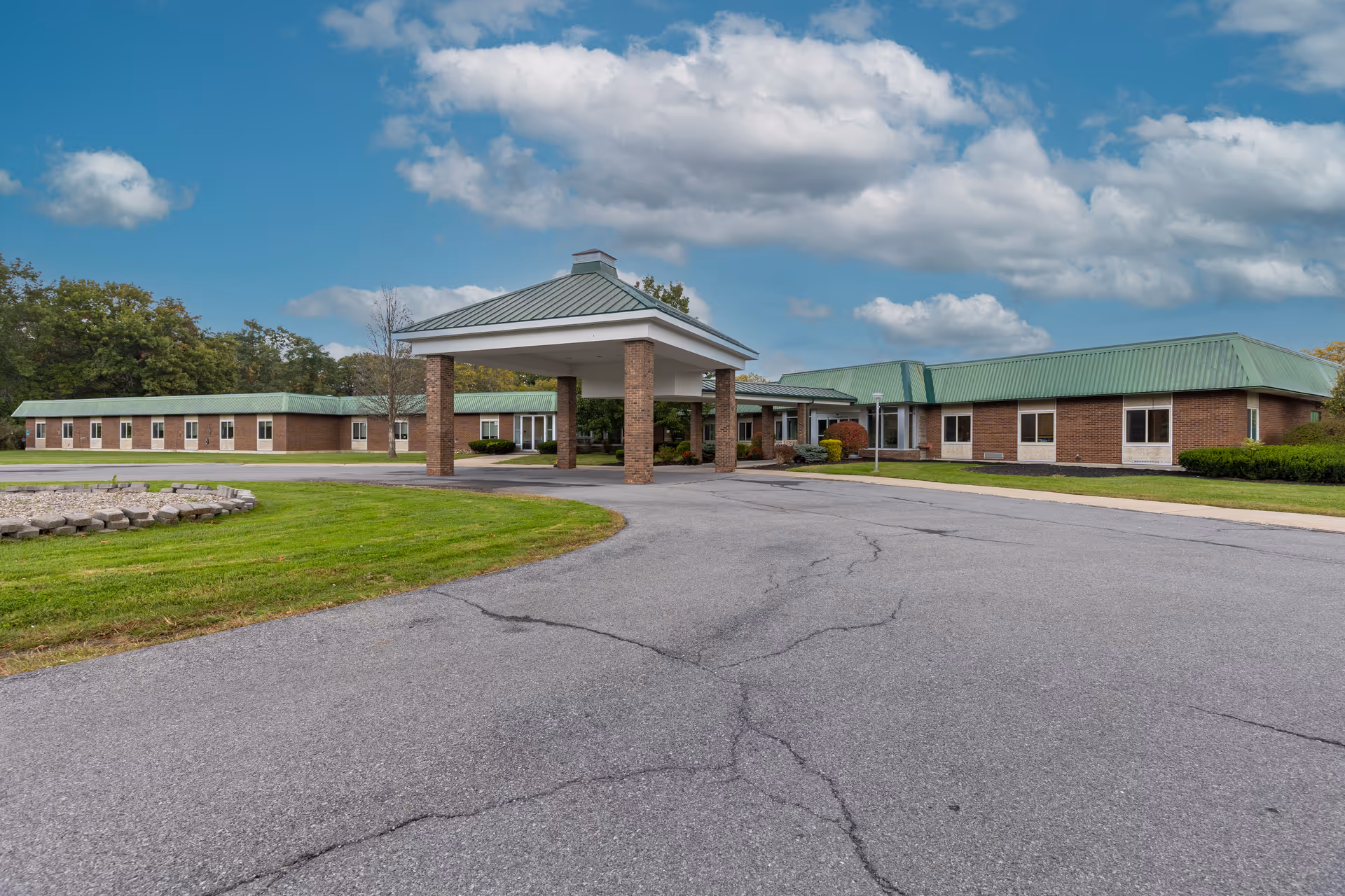Exterior view of River Ridge Living Center with brick building, green roofs, and driveway.