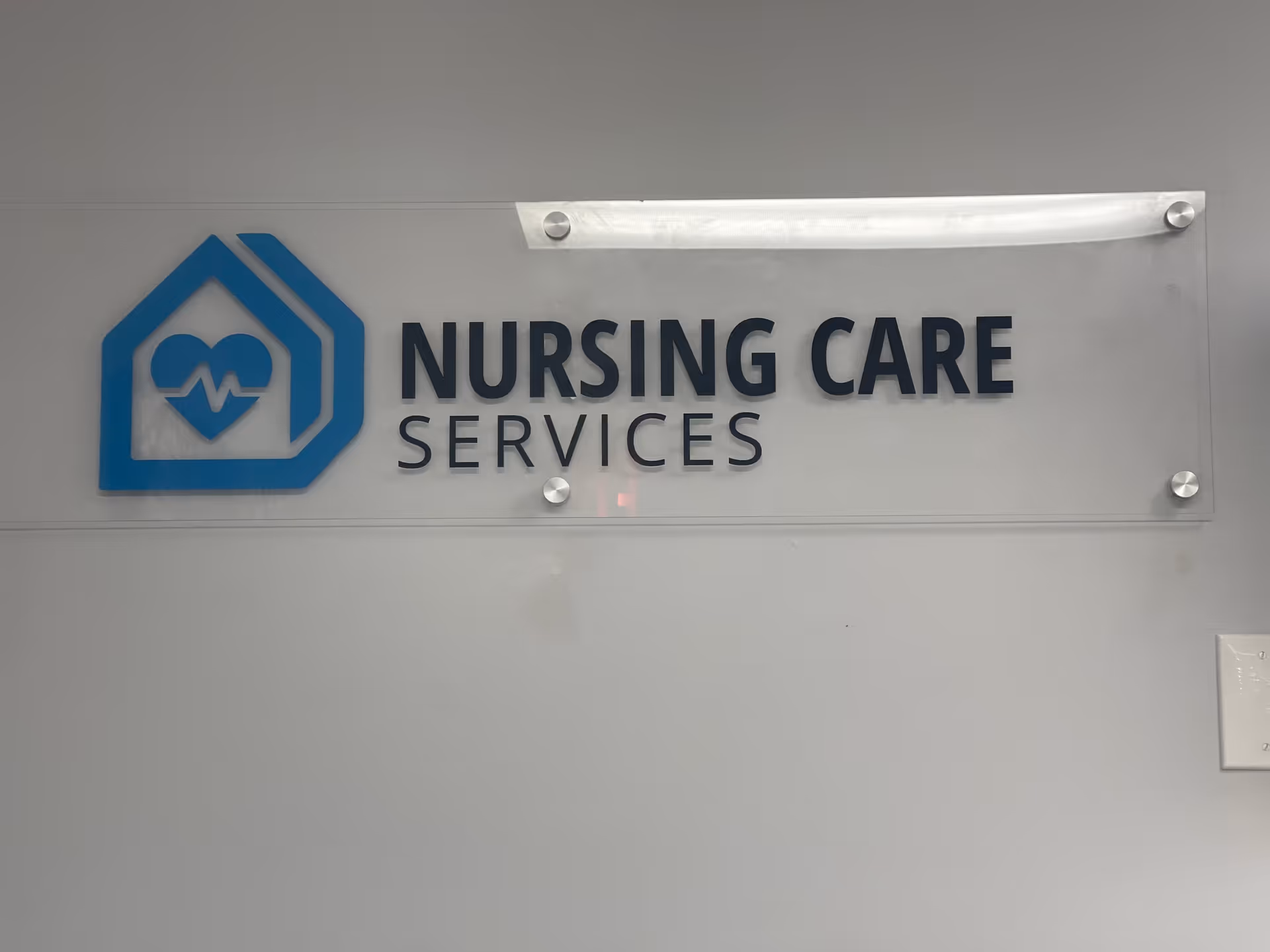 Interior wall plaque displaying Nursing Care Services logo and name