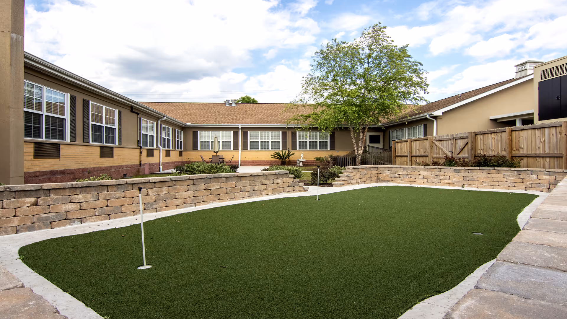 An outdoor courtyard at Nhc Health Care - Charleston with green turf and beige buildings.
