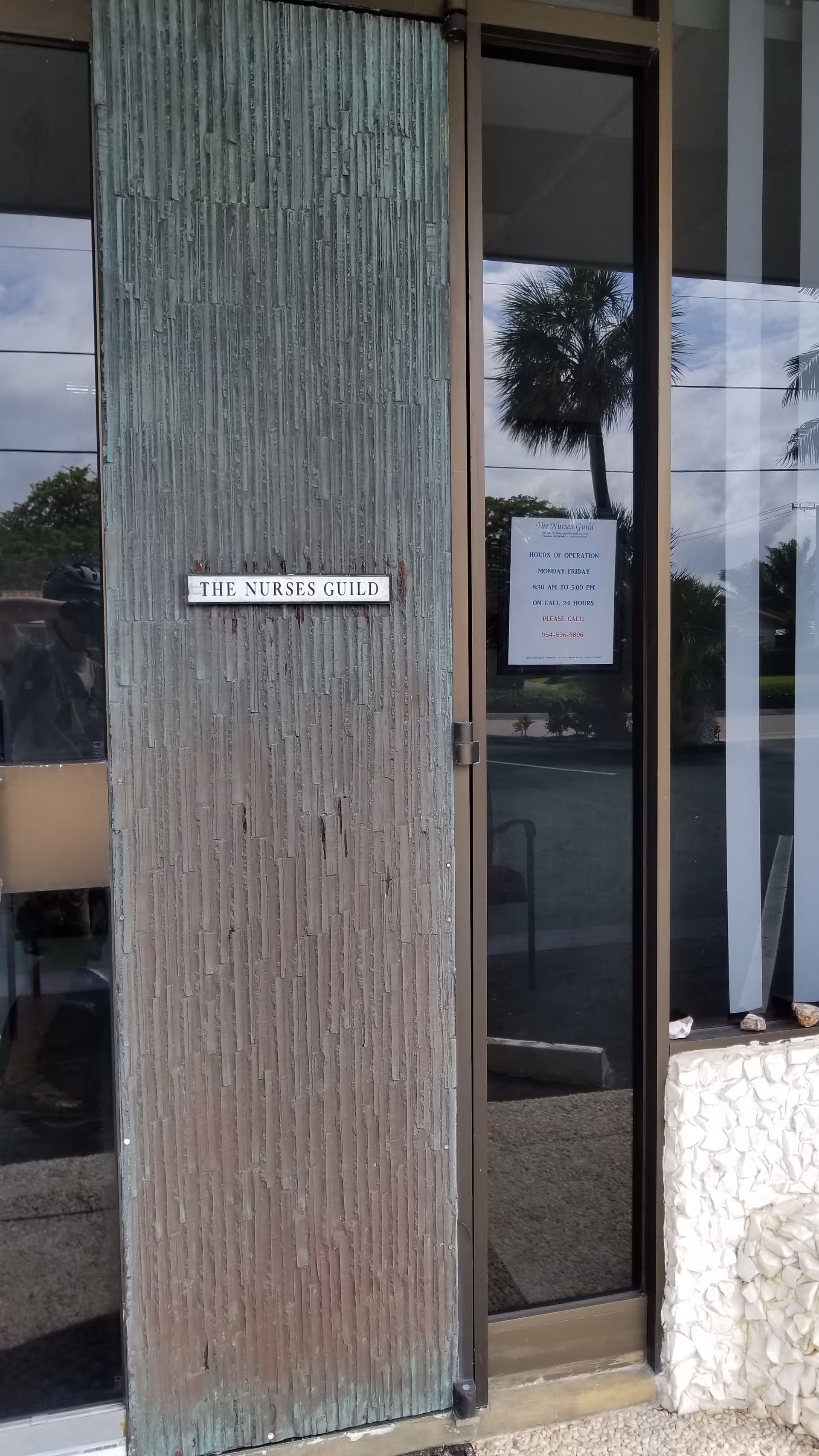 Exterior entrance to The Nurses Guild with glass doors and a textured wall.