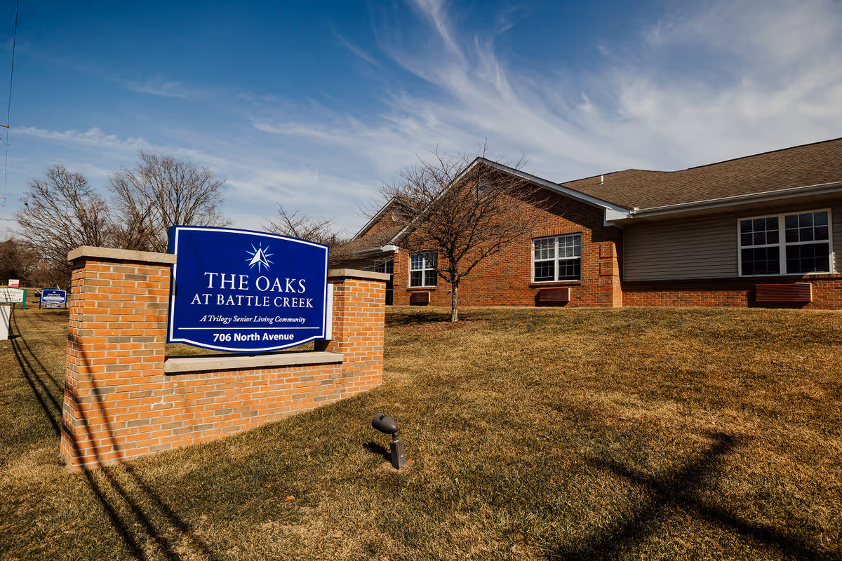 Exterior view of The Oaks at Battle Creek senior living facility with a blue sign.
