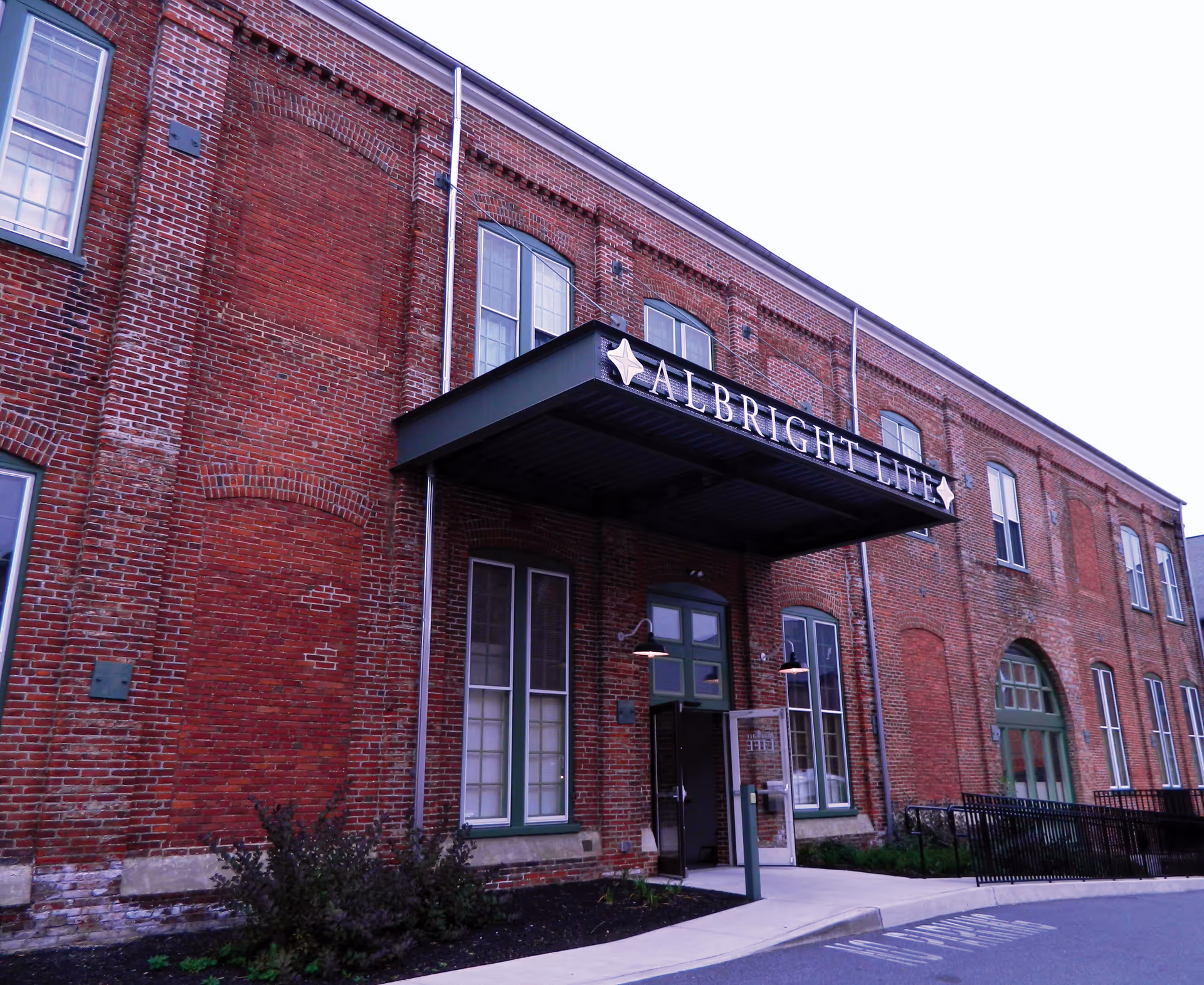A brick building exterior features a metal awning with the ALBRIGHT LIFE sign over the entrance.