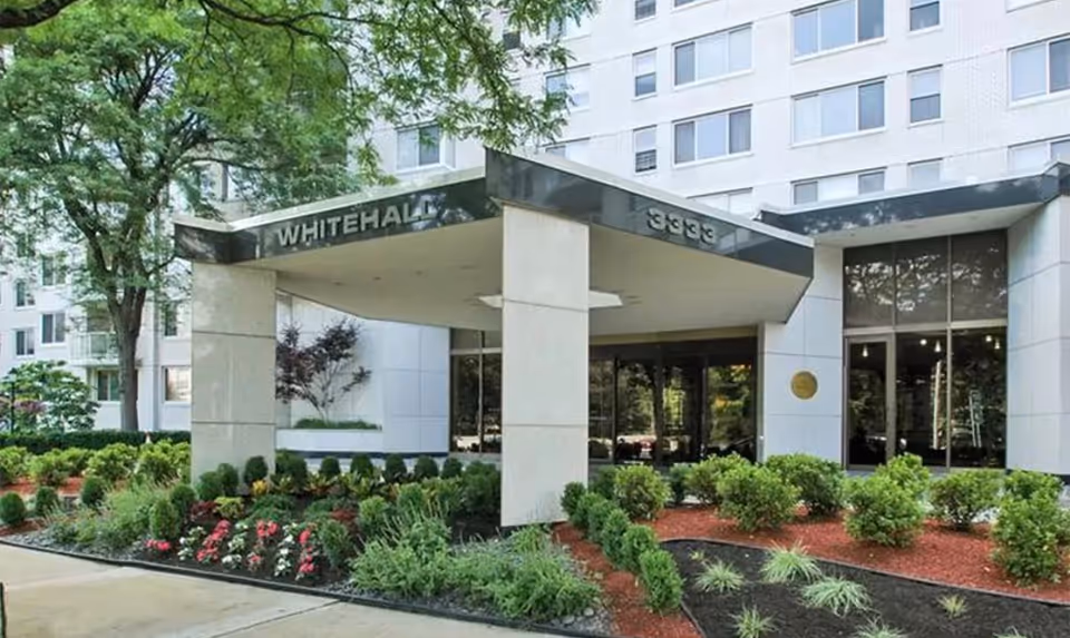 Entrance of a modern building with glass doors and surrounding landscaping.