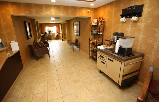 A tiled interior hallway/common area with seating and a coffee station labeled "Café" at a senior living facility.