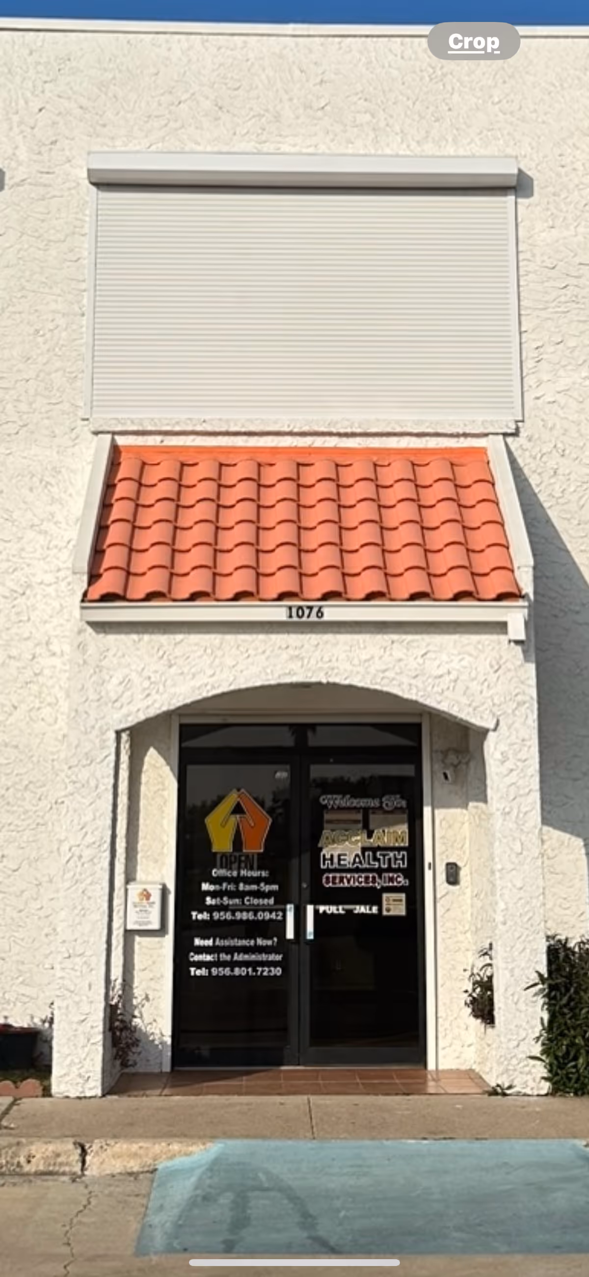Exterior view of a building entrance with a red-tiled awning and glass doors.