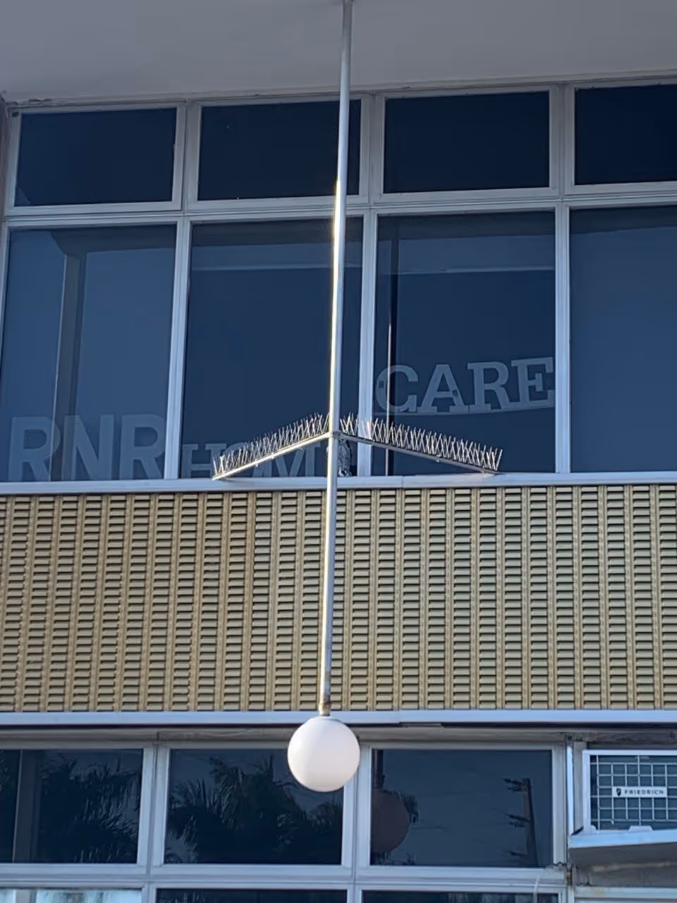 Facade of a senior living facility with large windows and long pole with a white sphere