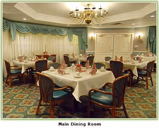 Elegant main dining room with round tables, chairs, chandeliers, and teal drapes.