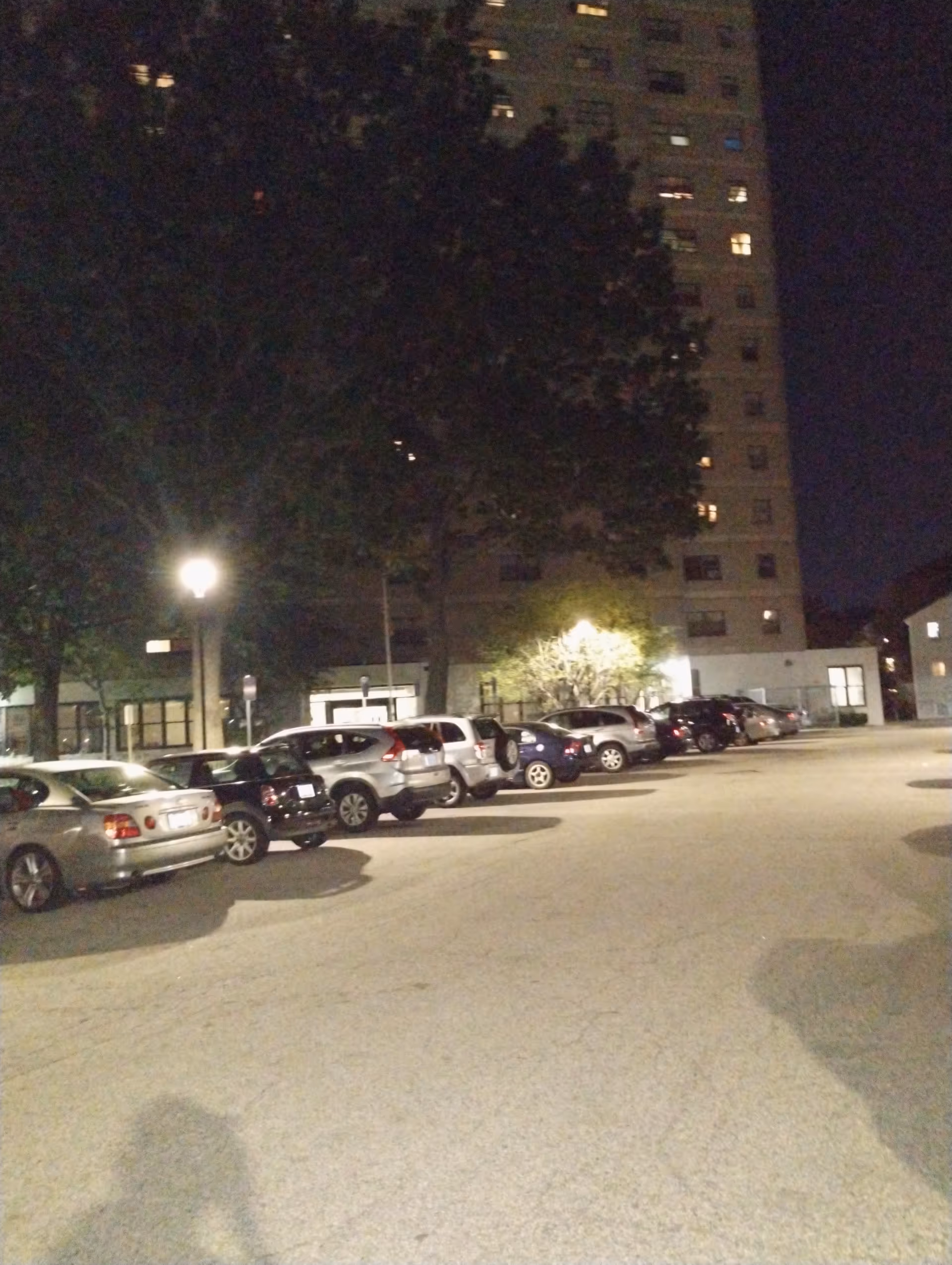 Night exterior of Carroll Tower with a parking lot and a lit building entrance.