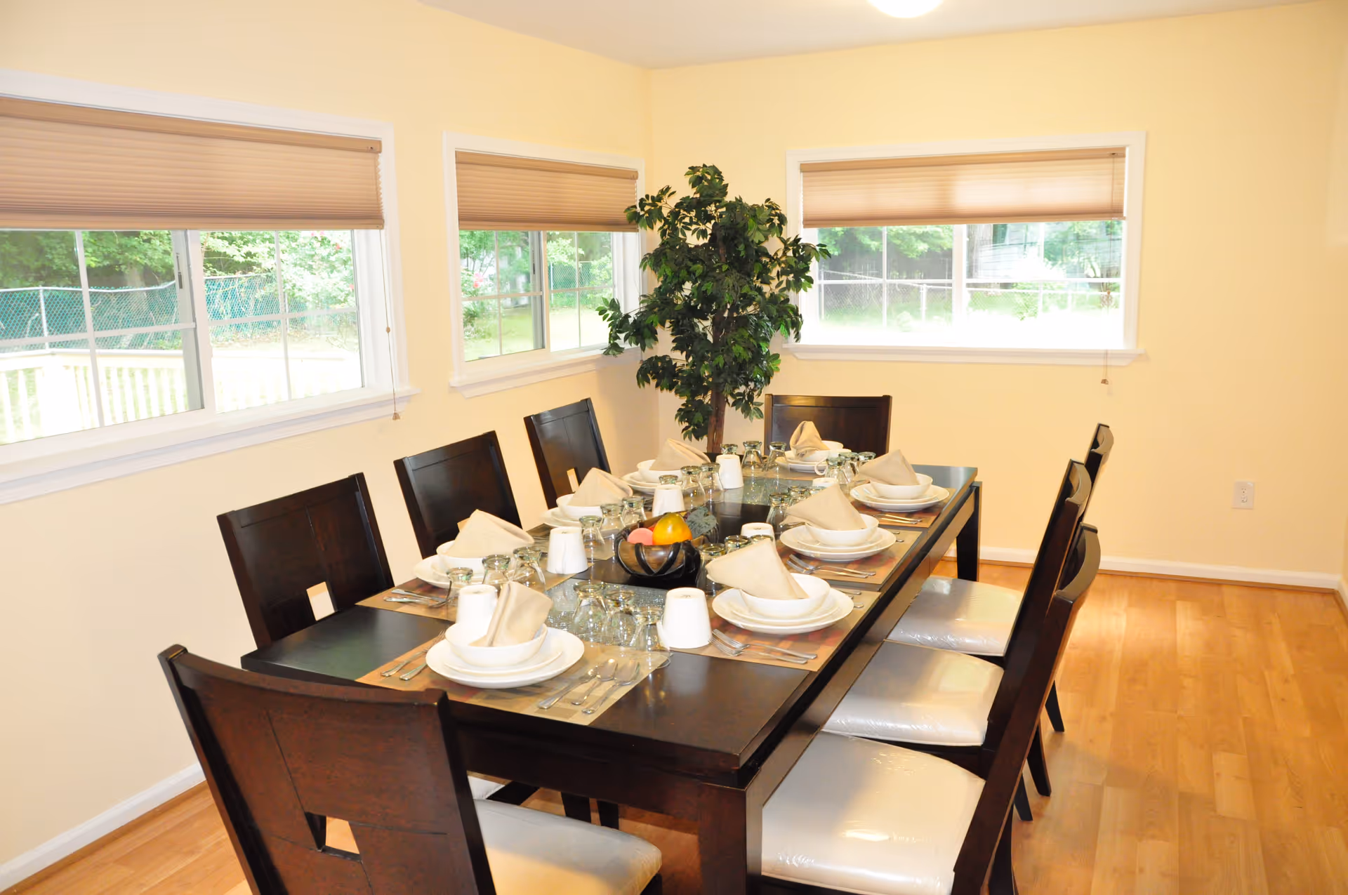 A long dining table set for a meal in a bright, furnished dining room.