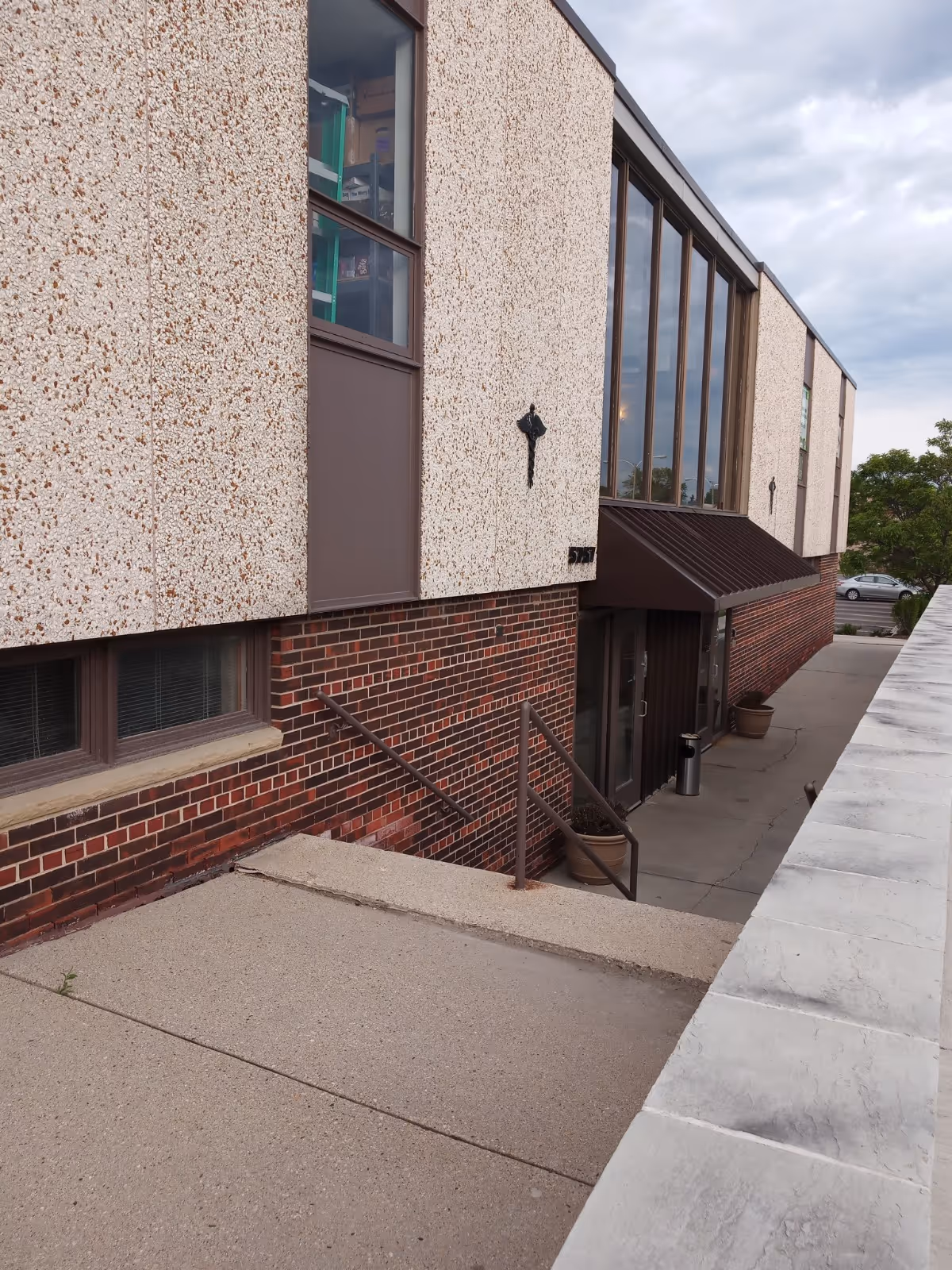 Exterior view of a brick and pebble-surfaced senior living facility with stairs.