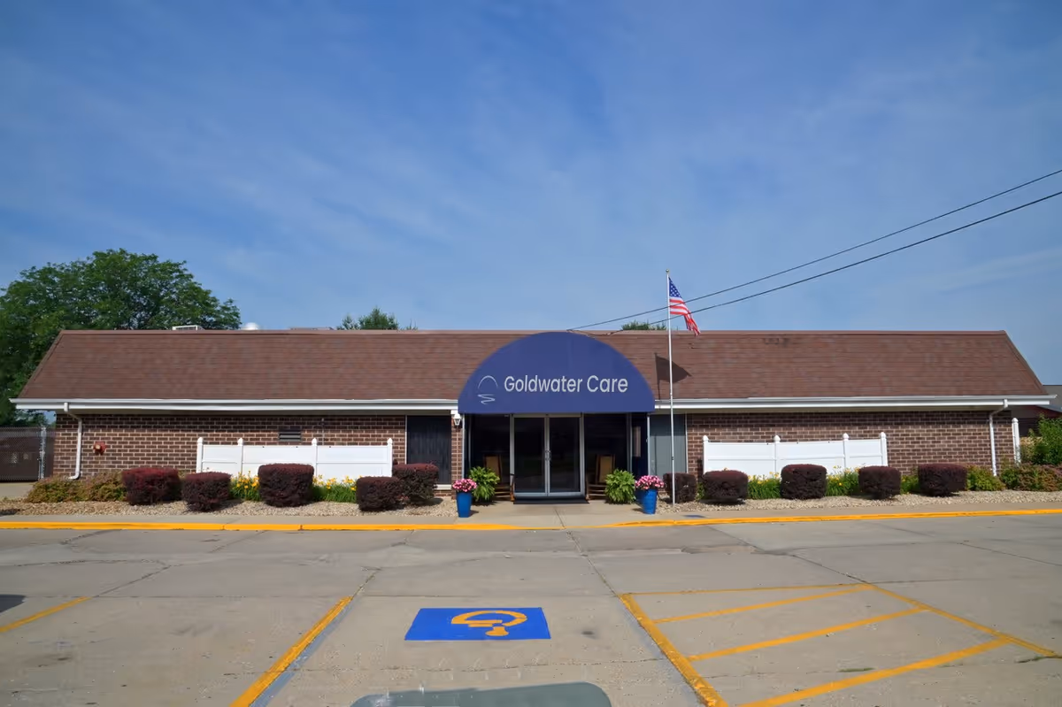 Front view of Goldwater Care with blue awning entrance and American flag.