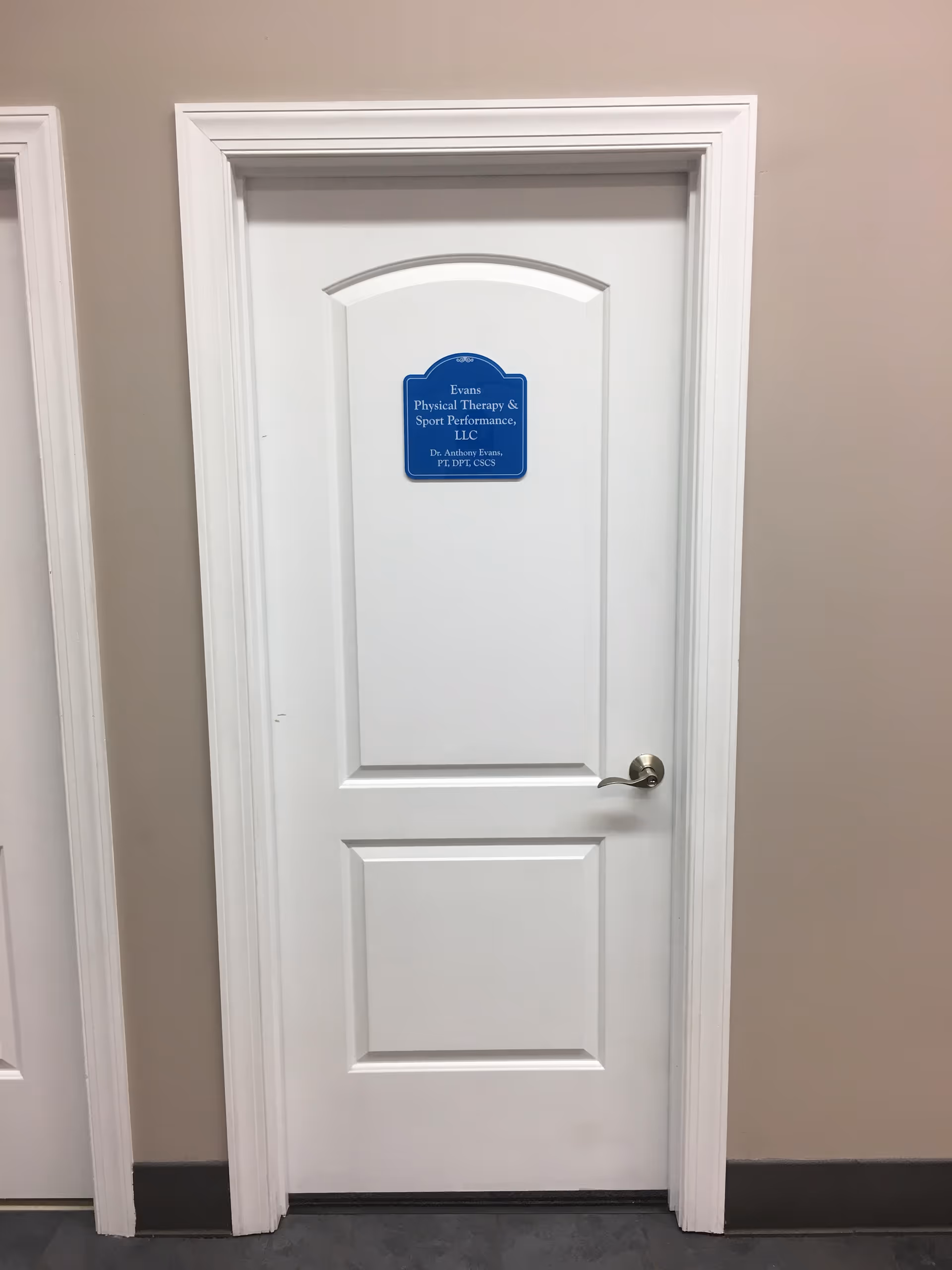White interior door with a blue Evans Physical Therapy & Sport Performance sign.