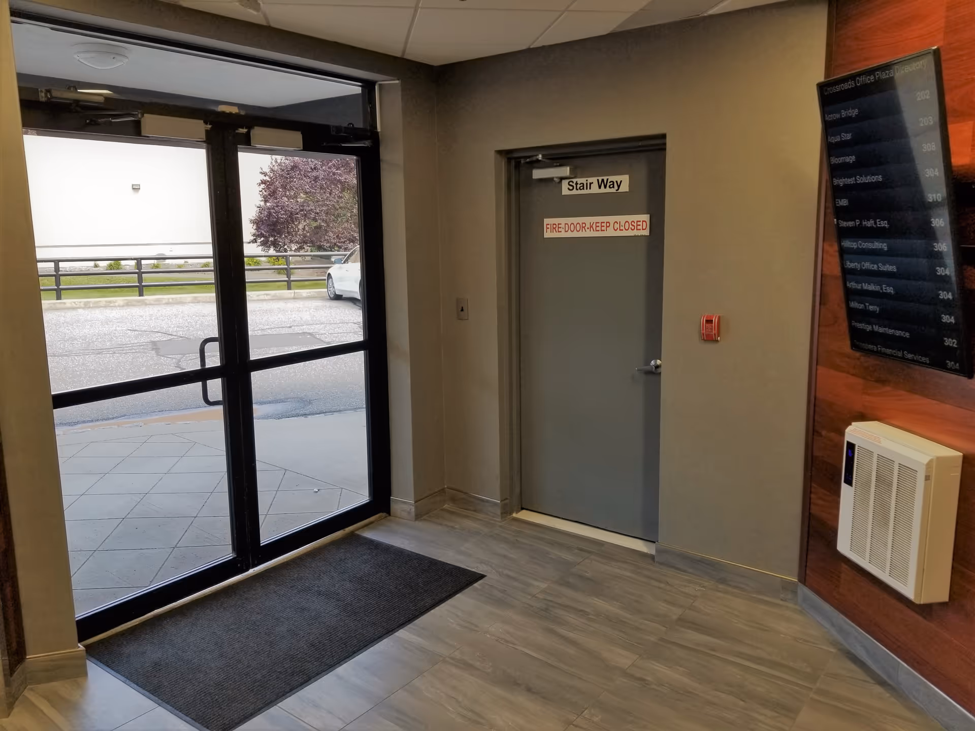 Interior hallway with glass entry doors and a labeled stairway door beside a directory.